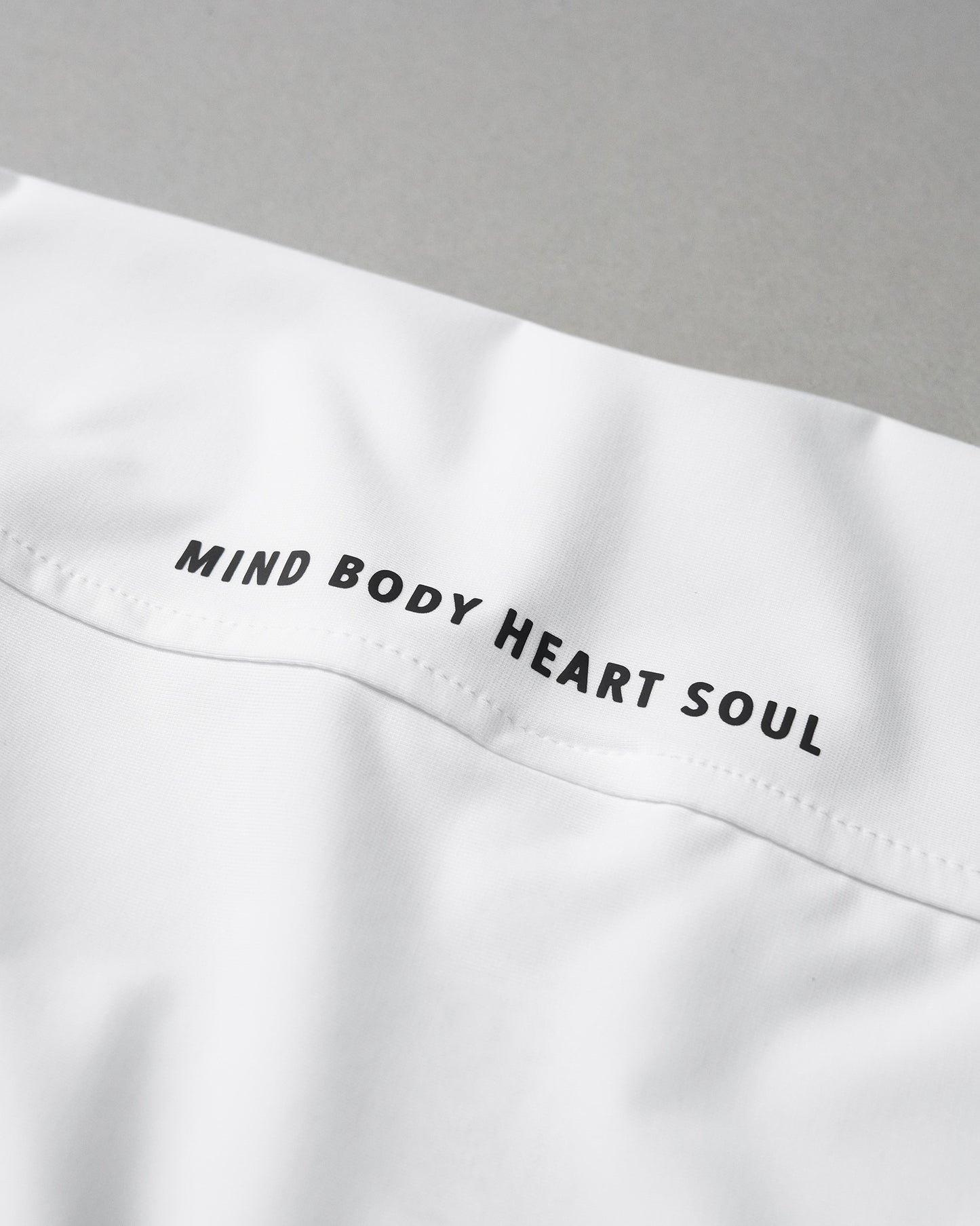 White garment with 'MIND BODY HEART SOUL' text on a gray background