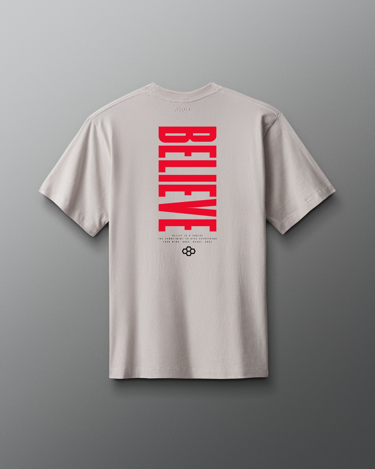 Beige t-shirt with red 'BELIEVE' text on the back against a gray background