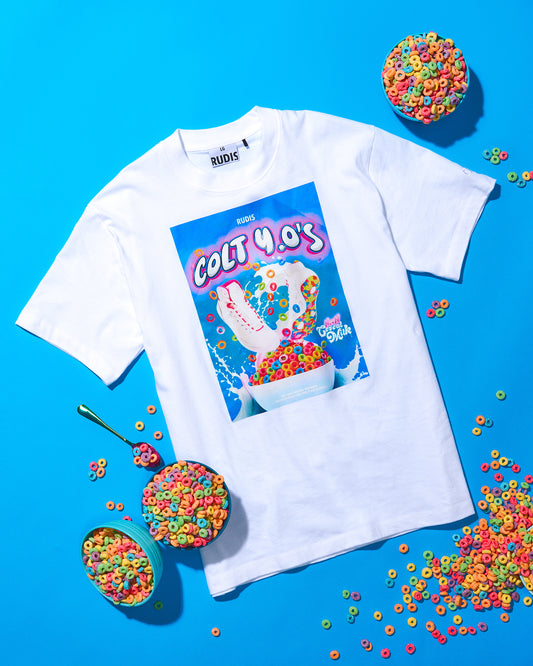 White t-shirt with a colorful graphic design on a blue background with cereal bowls.