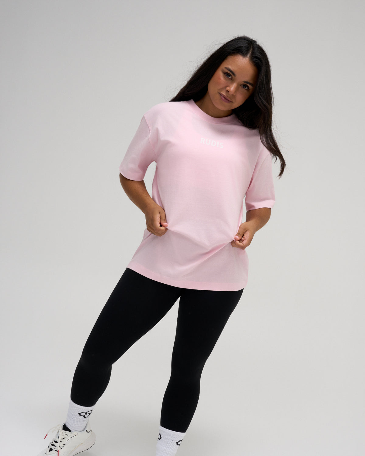 Female model wearing the RUDIS Wrestling Back Relaxed Cotton T-Shirt in Washed Pink, featuring a small white RUDIS chest logo, crew neckline, and relaxed fit.