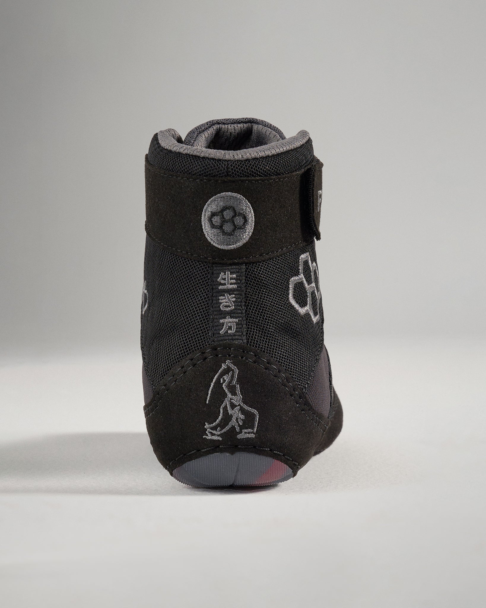 A close-up of a black and gray dog boot designed for protection and comfort featuring a secure strap and unique graphic elements on the back