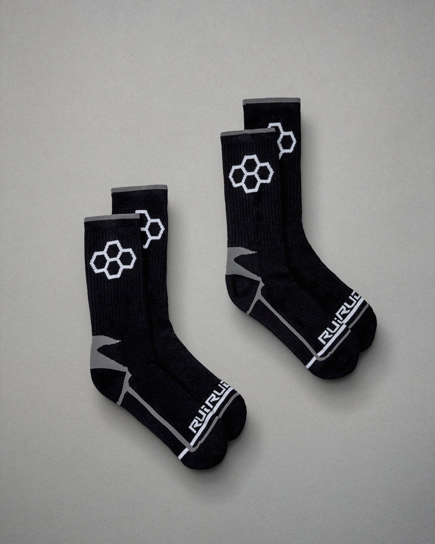 A pair of black athletic socks featuring a geometric design and branding on a gray background