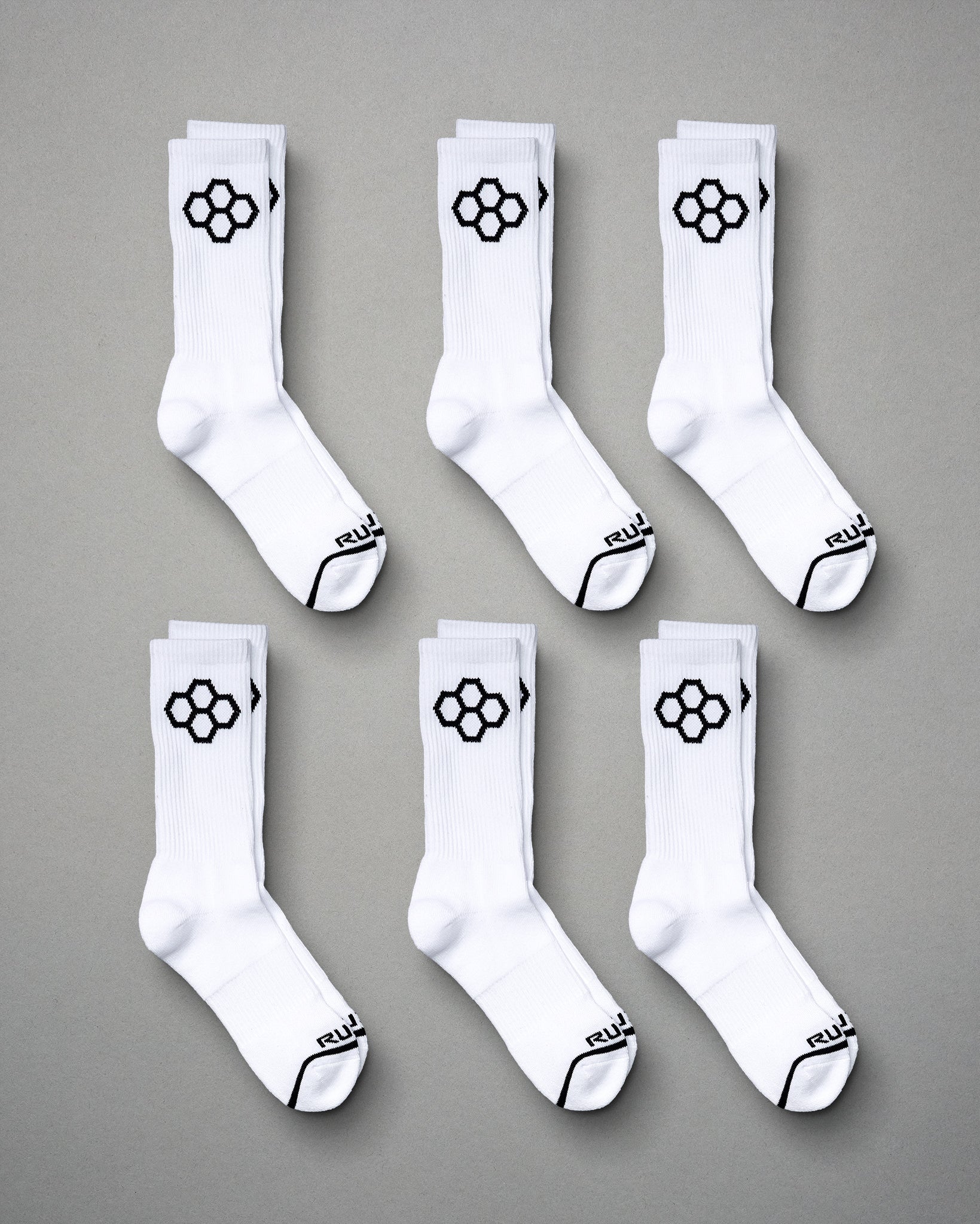 This image displays six pairs of white sports socks featuring a distinctive black hexagonal logo on the sides and black accents on the toes