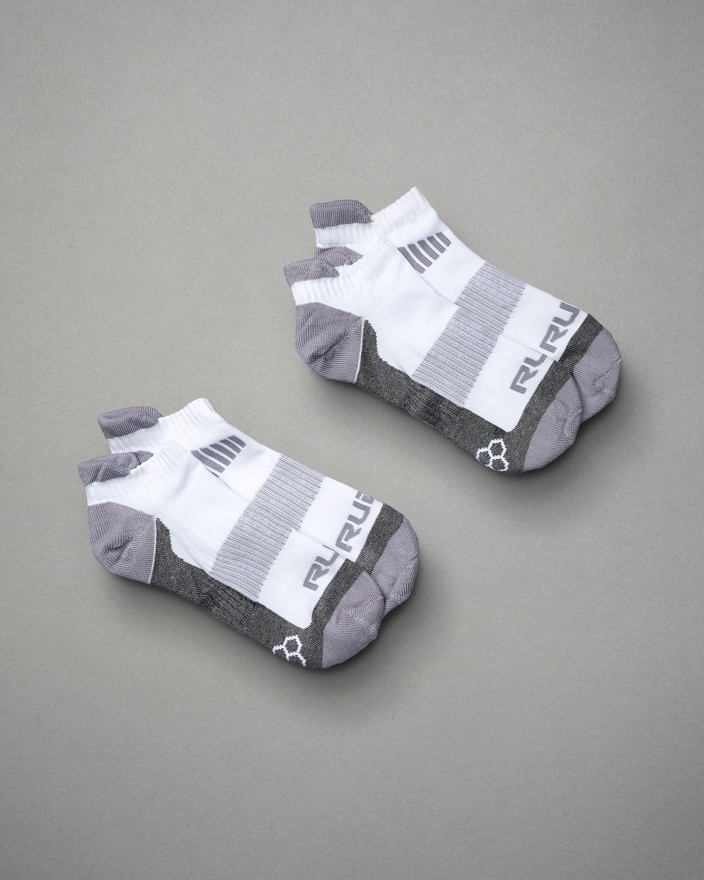 A pair of ankle sports socks featuring a modern design with a white upper and gray accents ideal for athletic wear