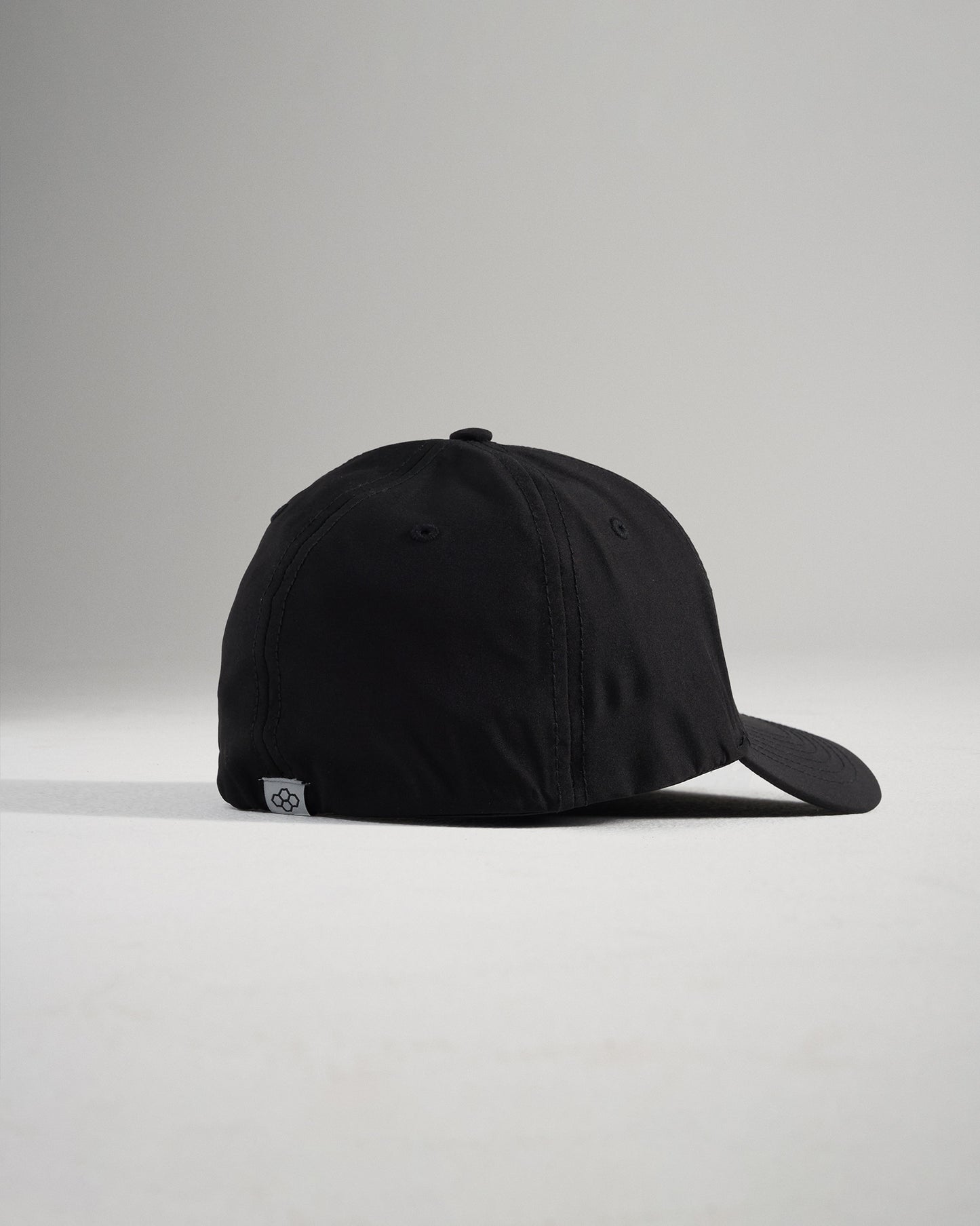 A stylish black baseball cap shown from a side angle featuring a curved brim and a subtle logo on the back