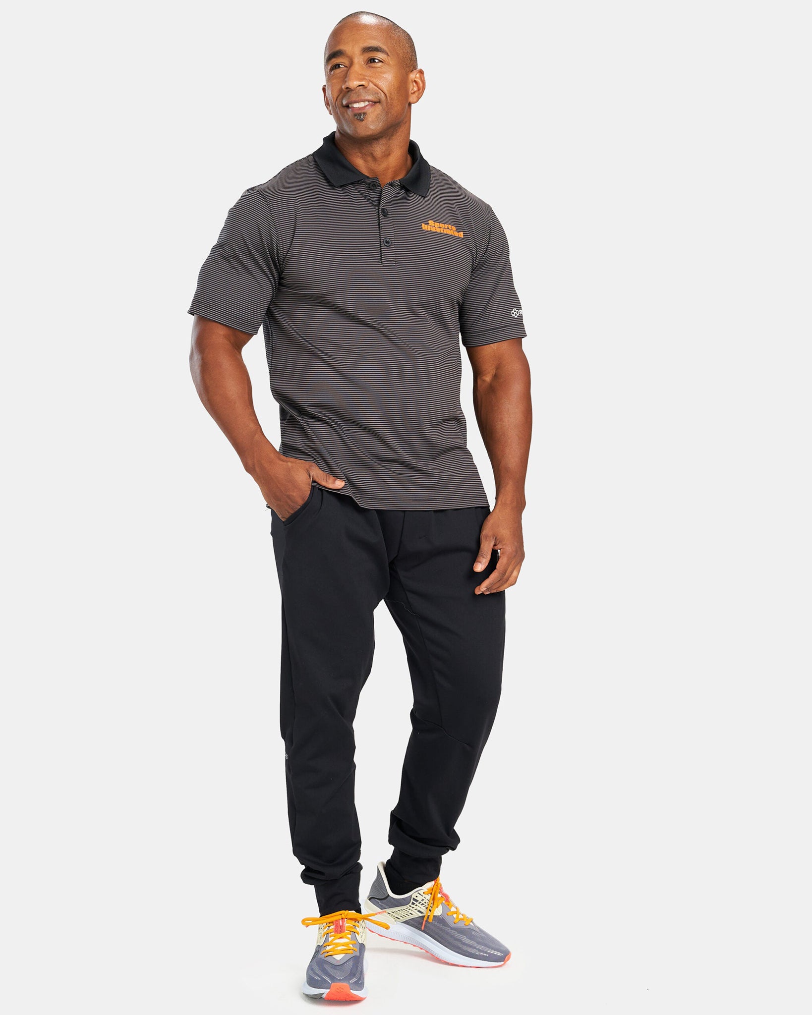 A fitness enthusiast poses in a sleek black polo shirt and black joggers complemented by colorful running shoes exuding a sporty and stylish aesthetic