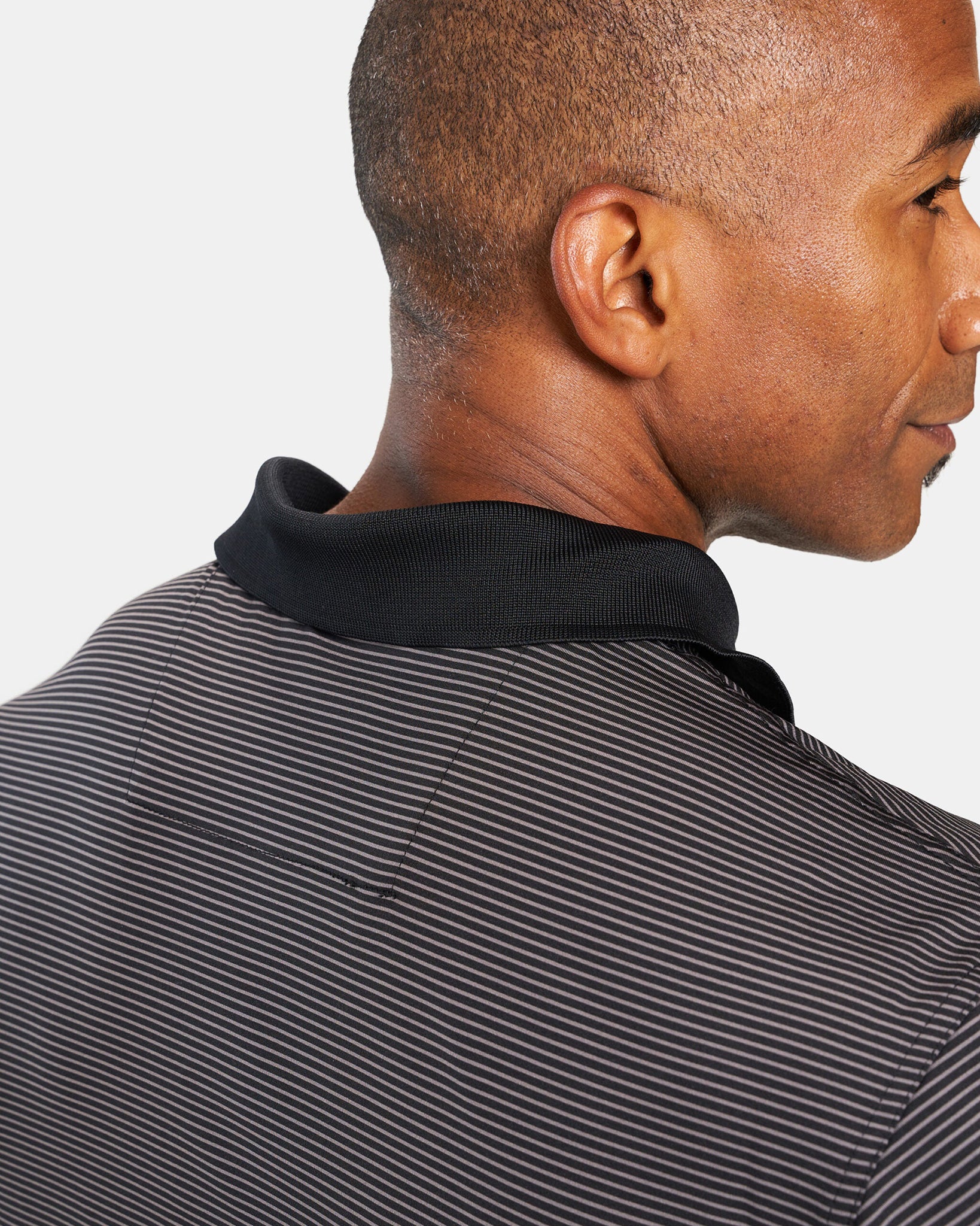 A close-up view of a mans collar and back of a striped polo shirt showcasing a stylish design and texture