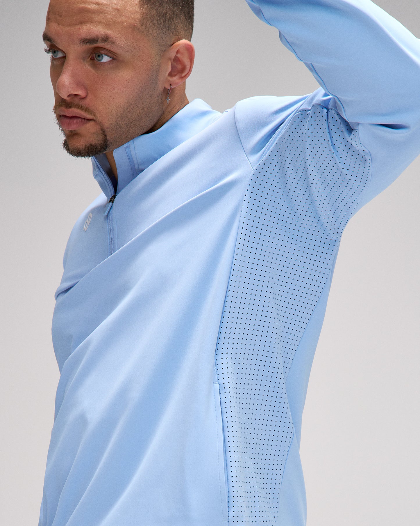Man wearing a light blue jacket with a textured pattern on a plain background