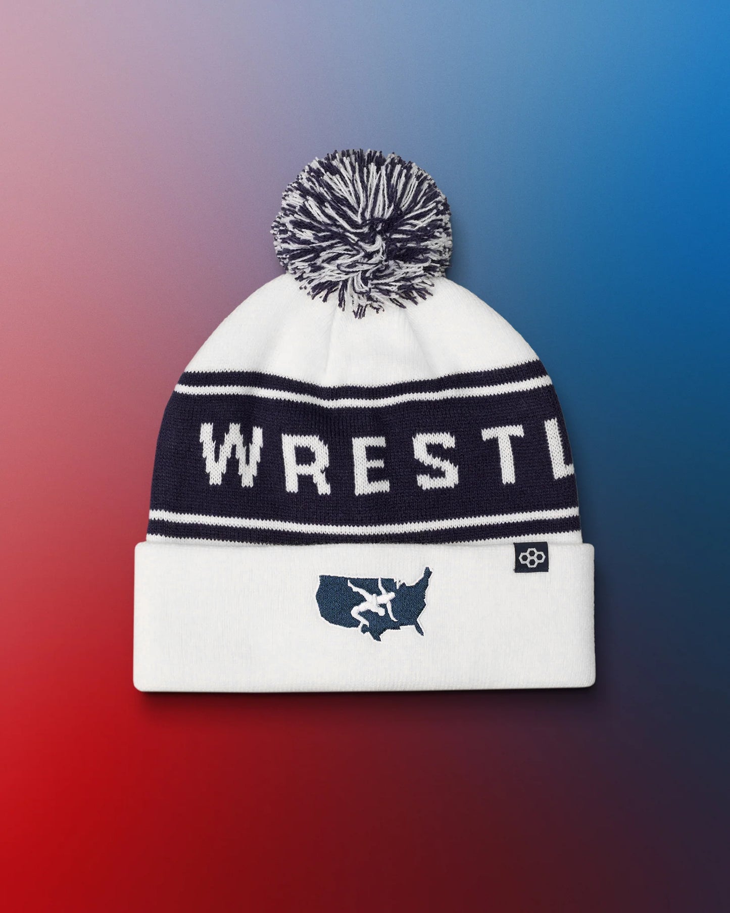 White beanie with 'WRESTLE' text and pom-pom on a gradient background with USA Wrestling logo