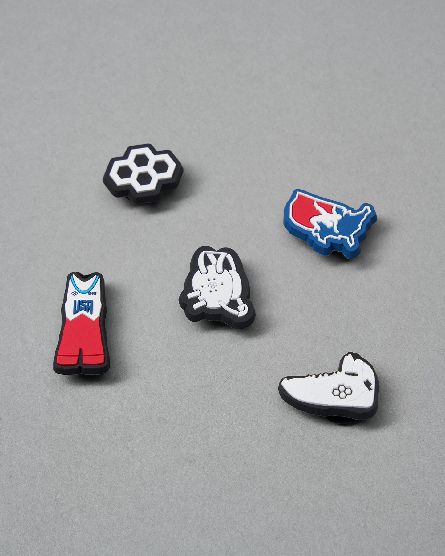 Five enamel pins with different designs on a gray background