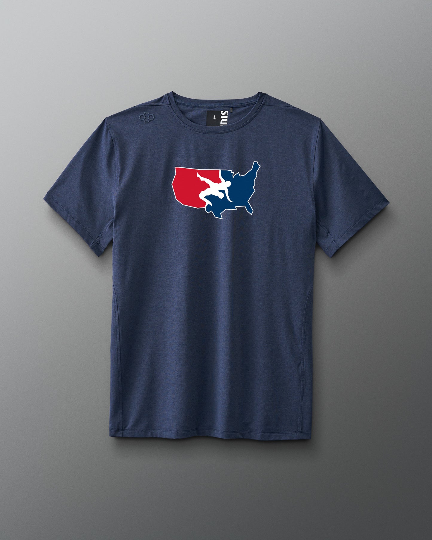 A navy blue short-sleeve athletic T-shirt is displayed against a gray background. Centered on the chest is a red, white, and blue USA Wrestling logo shaped like the continental United States, featuring two wrestlers in action. The shirt has a modern athletic fit.