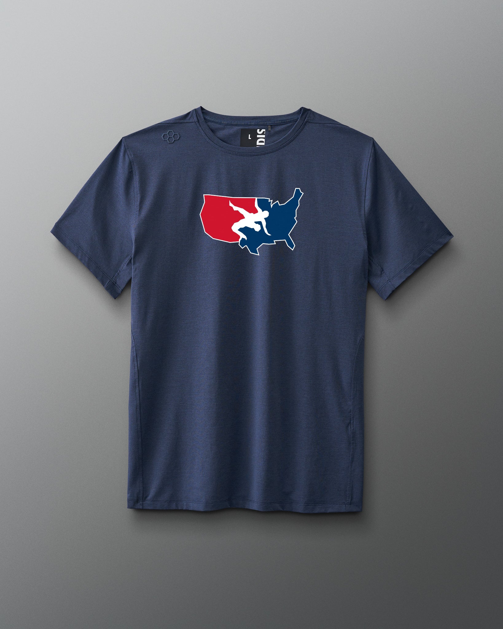 A navy blue short-sleeve athletic T-shirt is displayed against a gray background. Centered on the chest is a red, white, and blue USA Wrestling logo shaped like the continental United States, featuring two wrestlers in action. The shirt has a modern athletic fit.