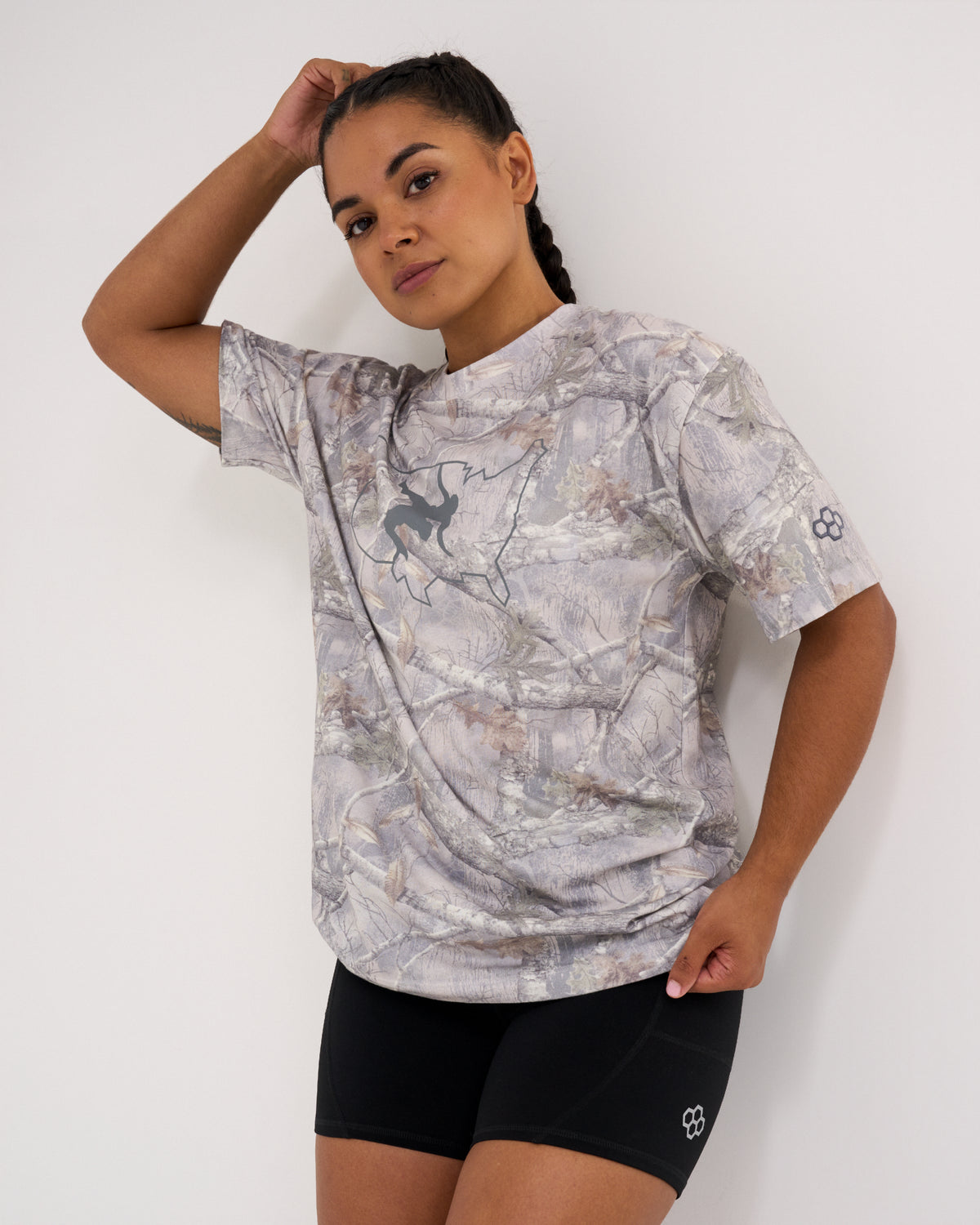 Female model wearing the USA Wrestling Map Classic Cotton T-Shirt in light gray tree camo, featuring a gray wrestling silhouette inside a USA map outline, paired with black athletic shorts.