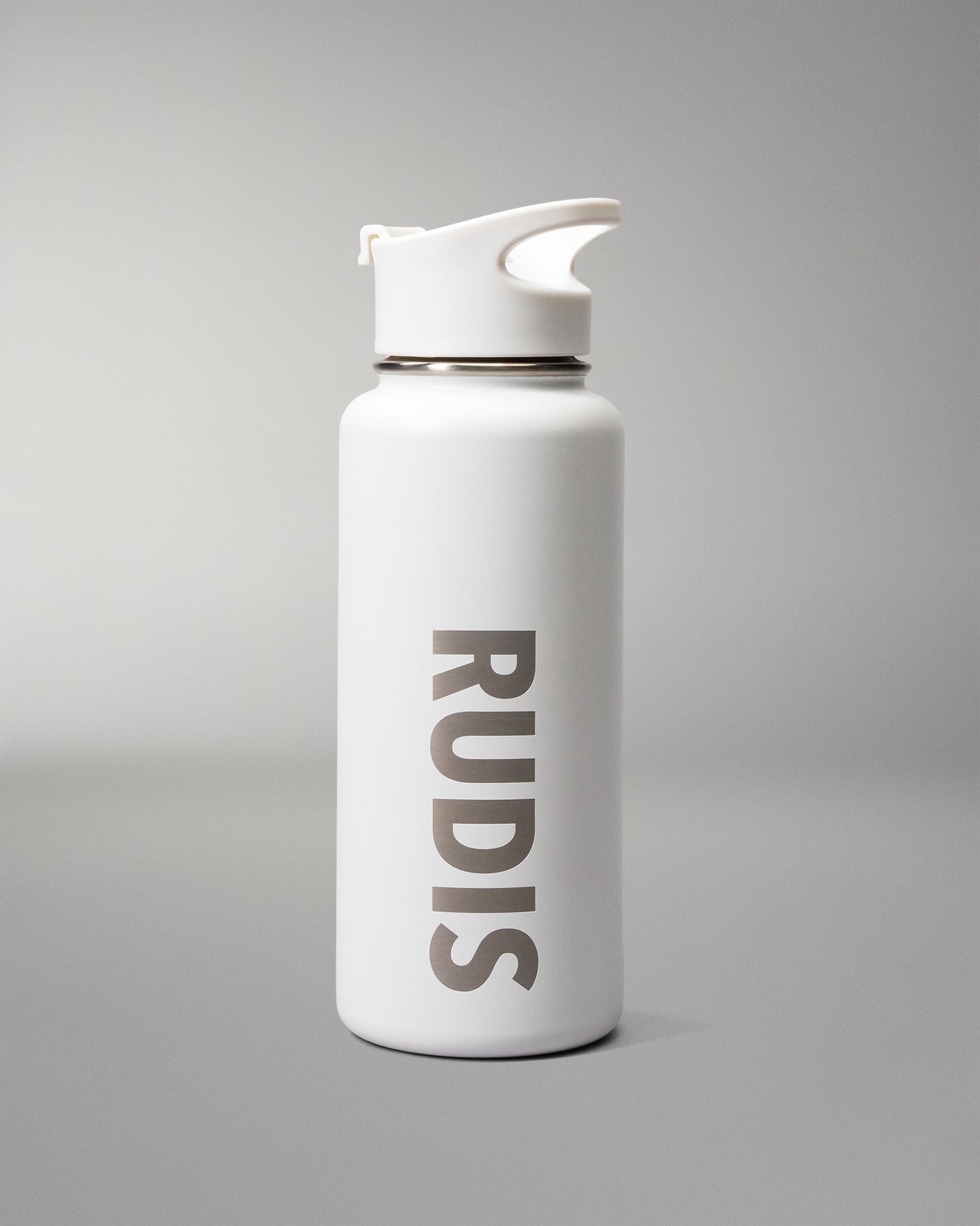 A white insulated water bottle with a matching white flip-top lid, featuring the brand name 'RUDIS' printed vertically in dark gray on the front, set against a neutral gray background.