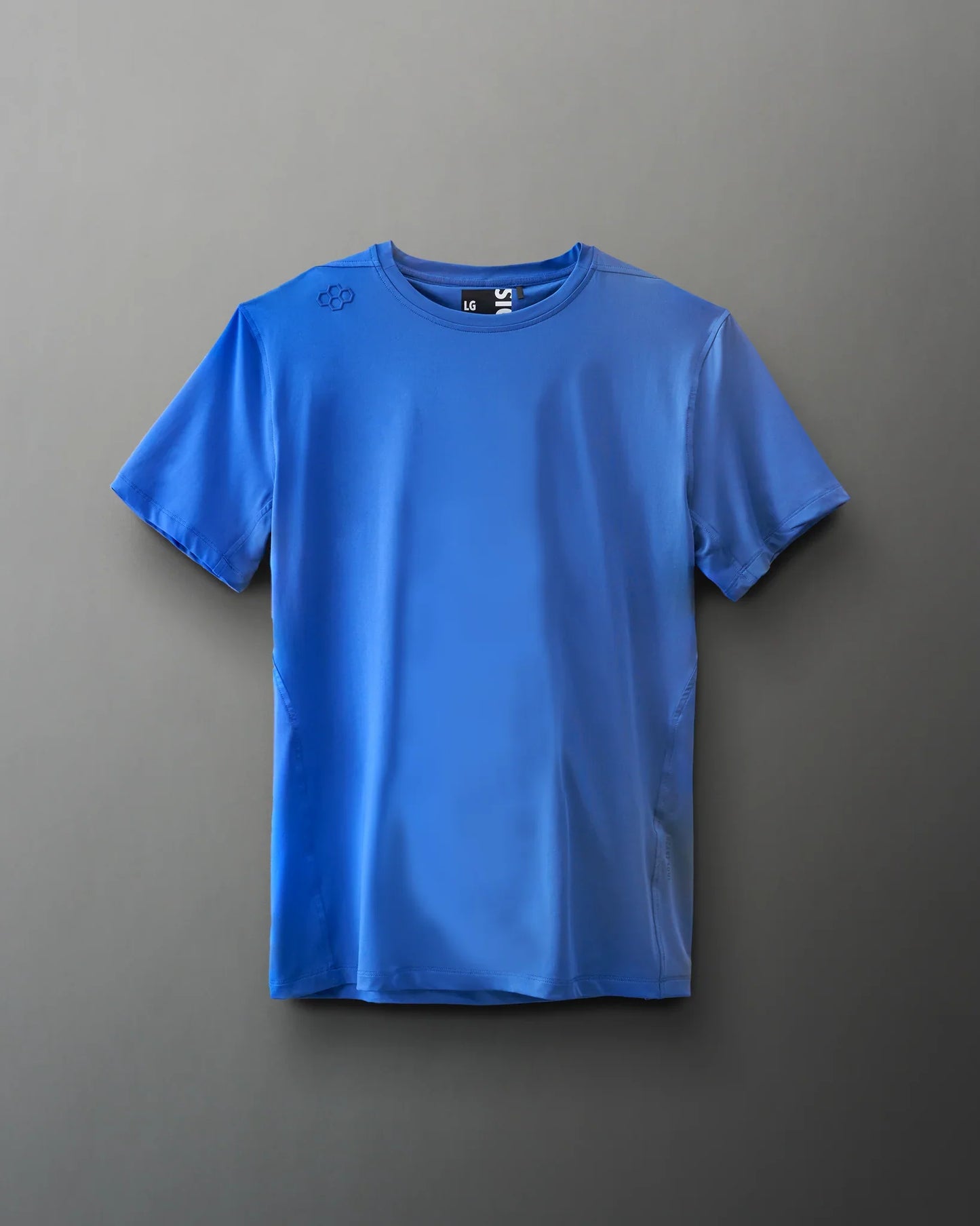 A blue athletic t-shirt hangs against a soft gray background, showcasing its lightweight fabric and brand logo on the shoulder.