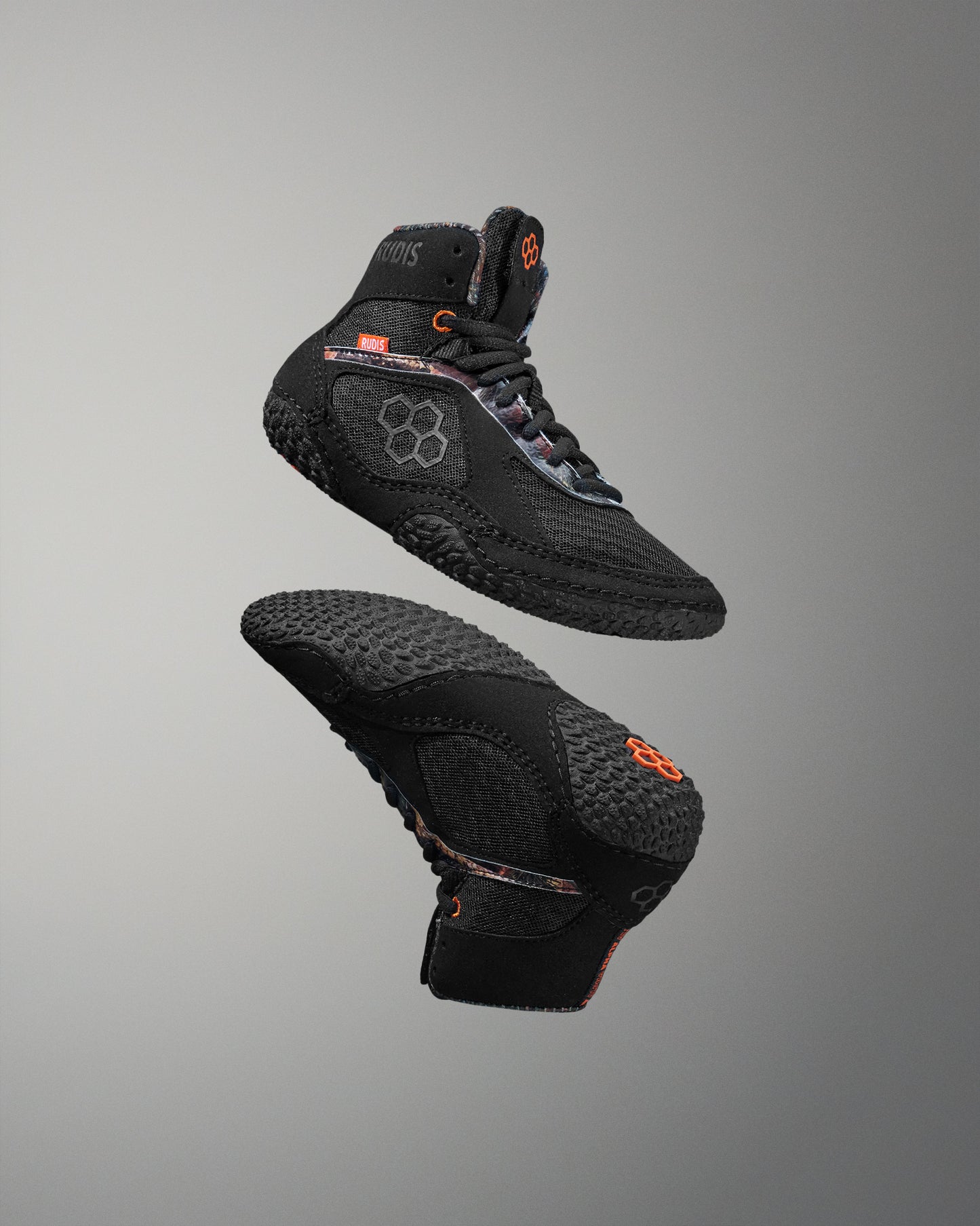 Black wrestling shoe with orange accents on a gray background