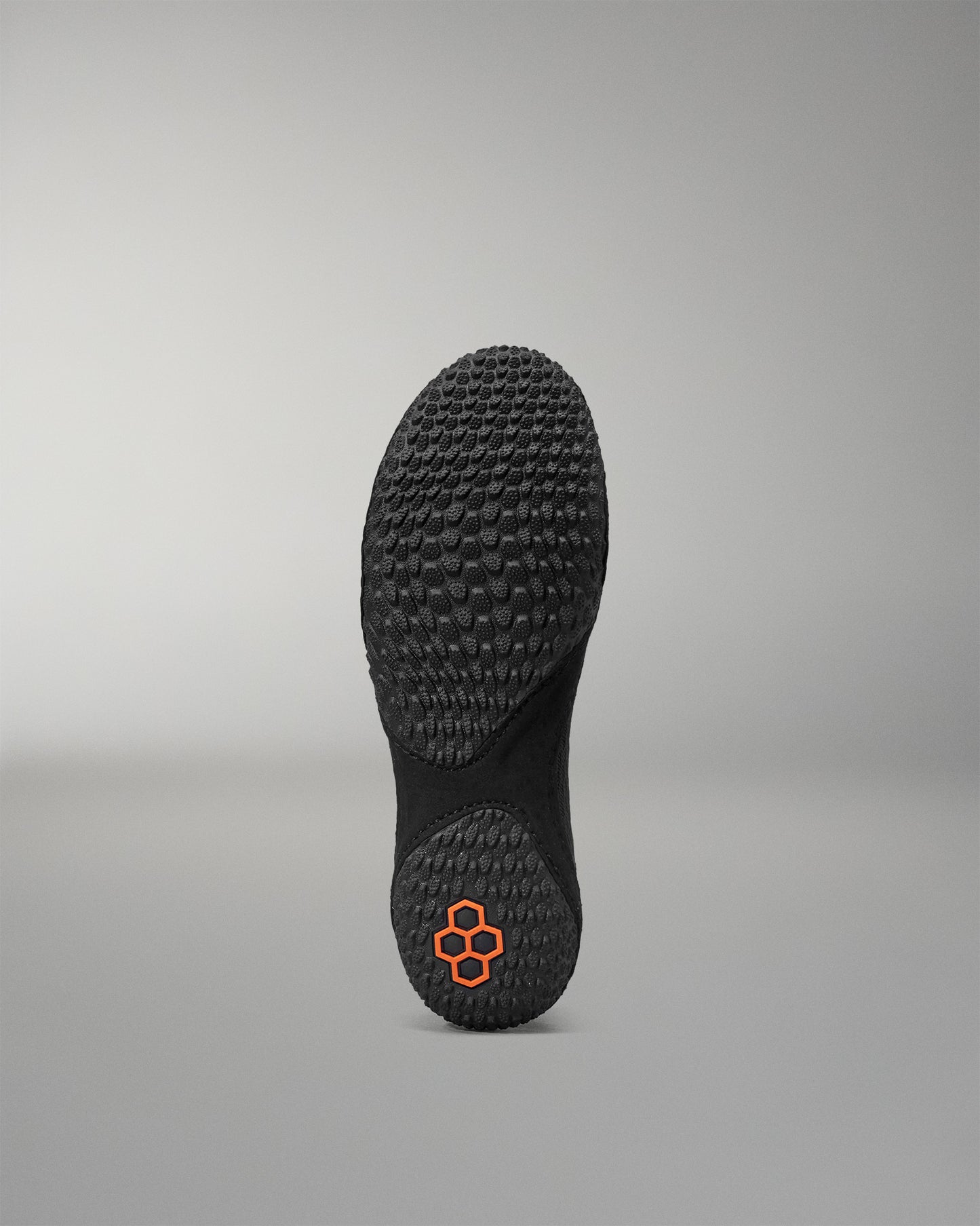 Black sole of a shoe with a unique tread pattern on a gray background