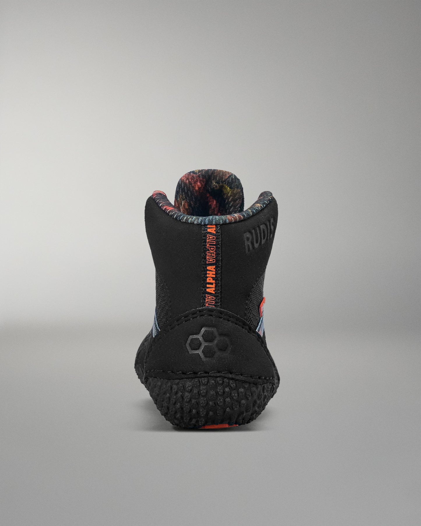 Black wrestling shoe with red and blue accents on a gray background