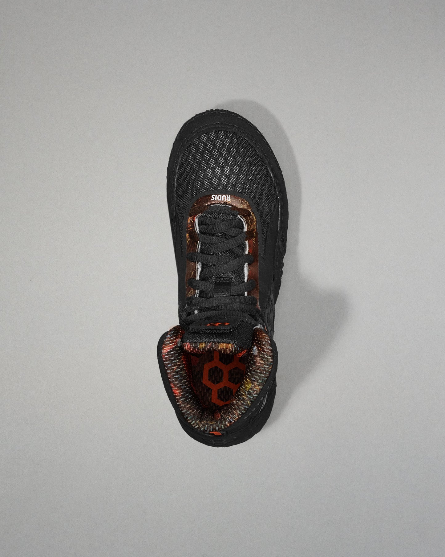 Black sneaker with a unique sole design on a gray background