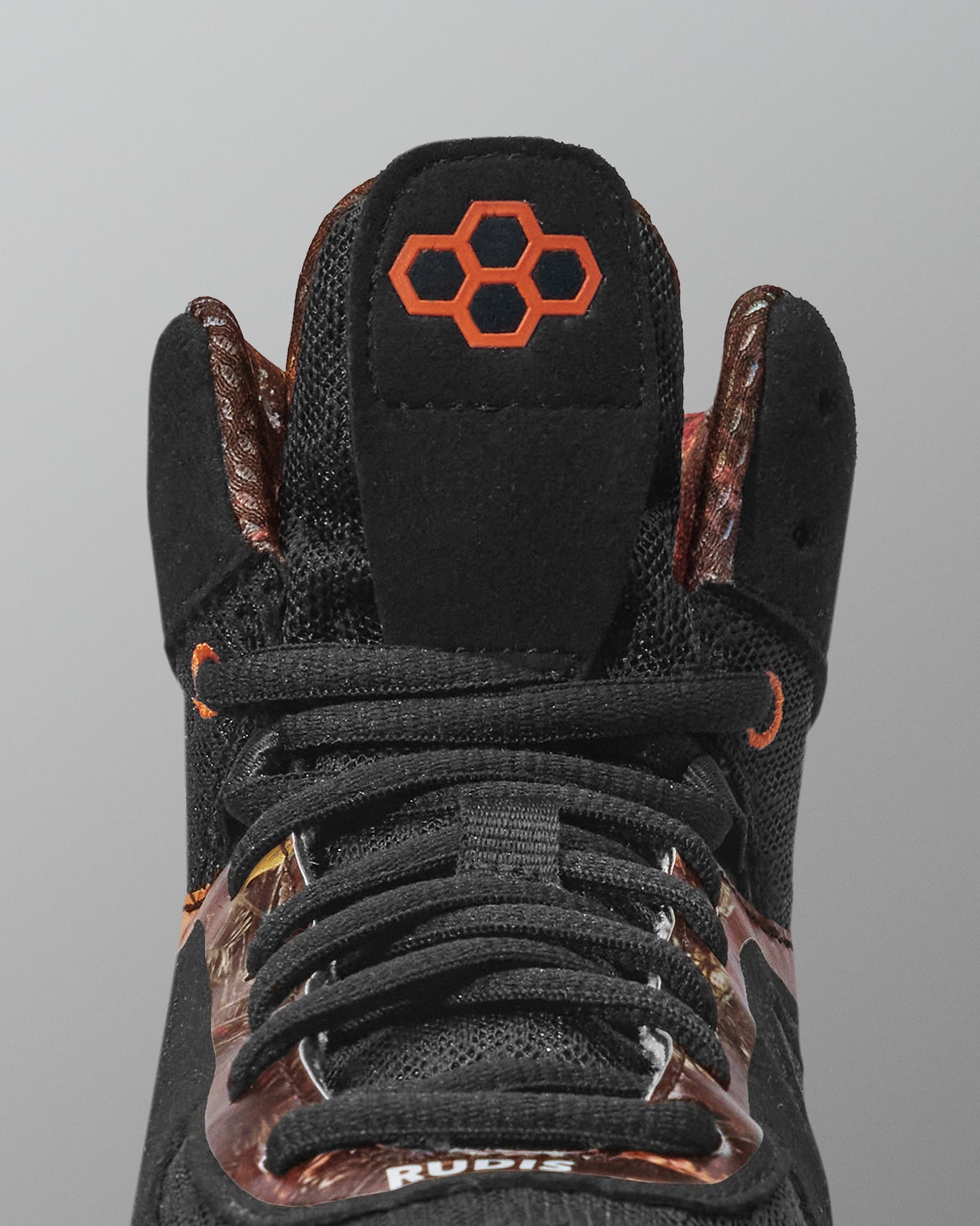 Black sneaker with brown accents and a hexagonal logo on a gray background