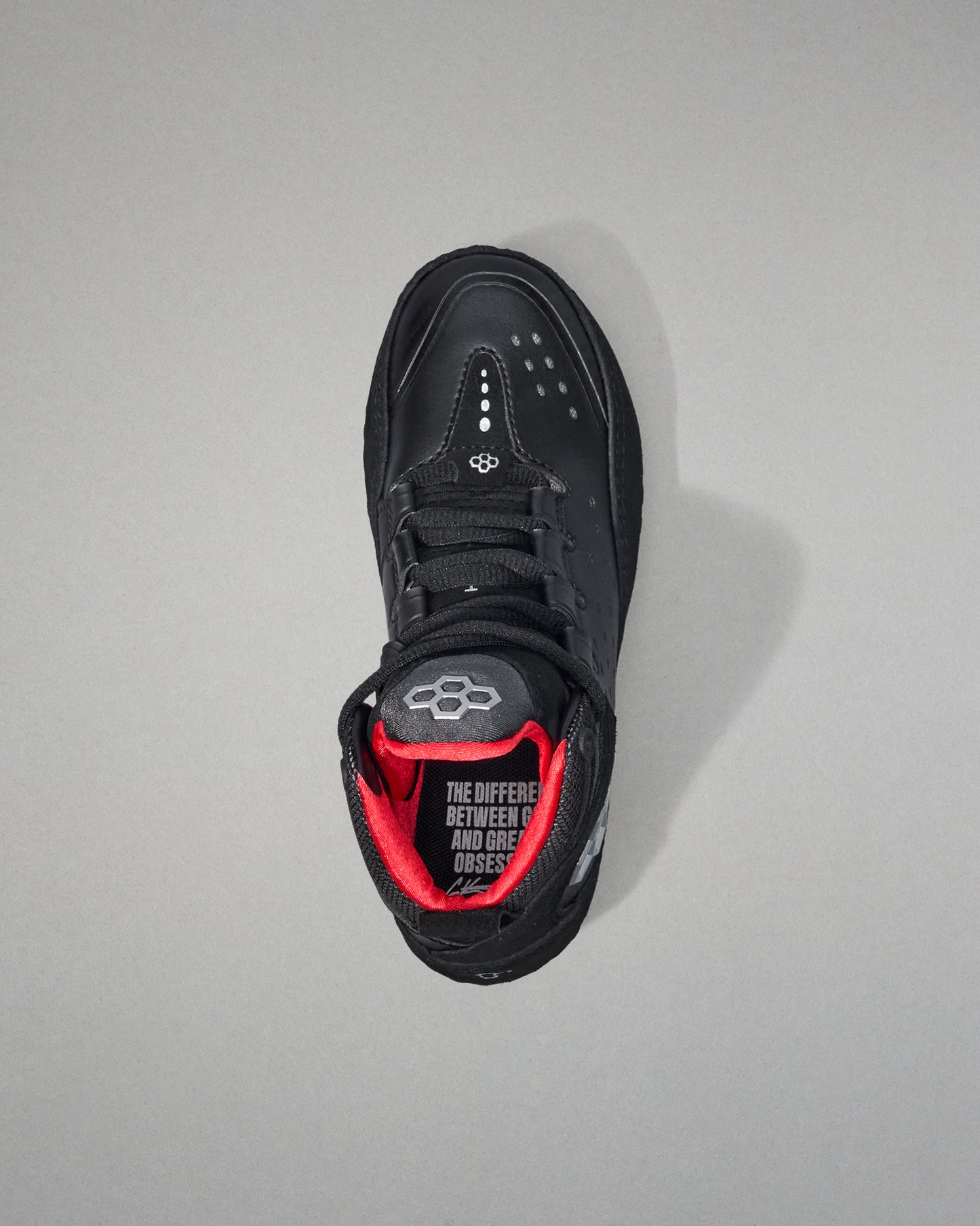 Black wrestling shoe with red interior on a gray background