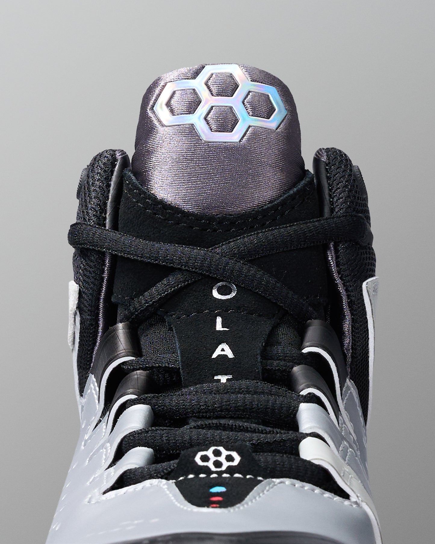 Close-up of a black and gray wrestling shoe with a hexagonal pattern on a gray background