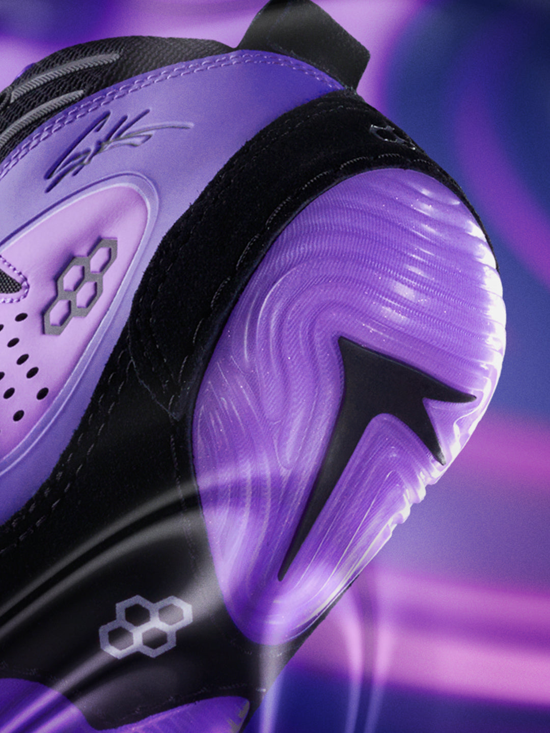 Close-up of a black and purple wrestling shoe with a prominent brand logo on a dark background