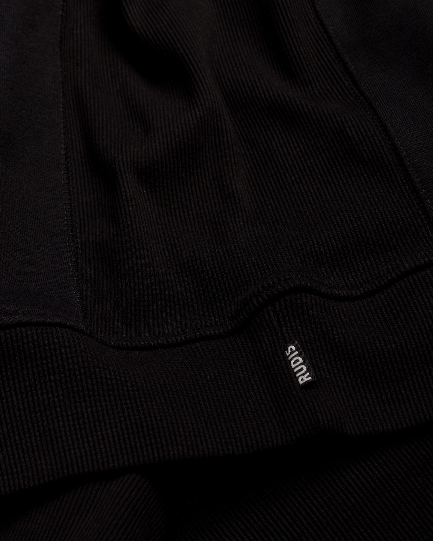 Close-up of a black garment with a brand logo on a dark background