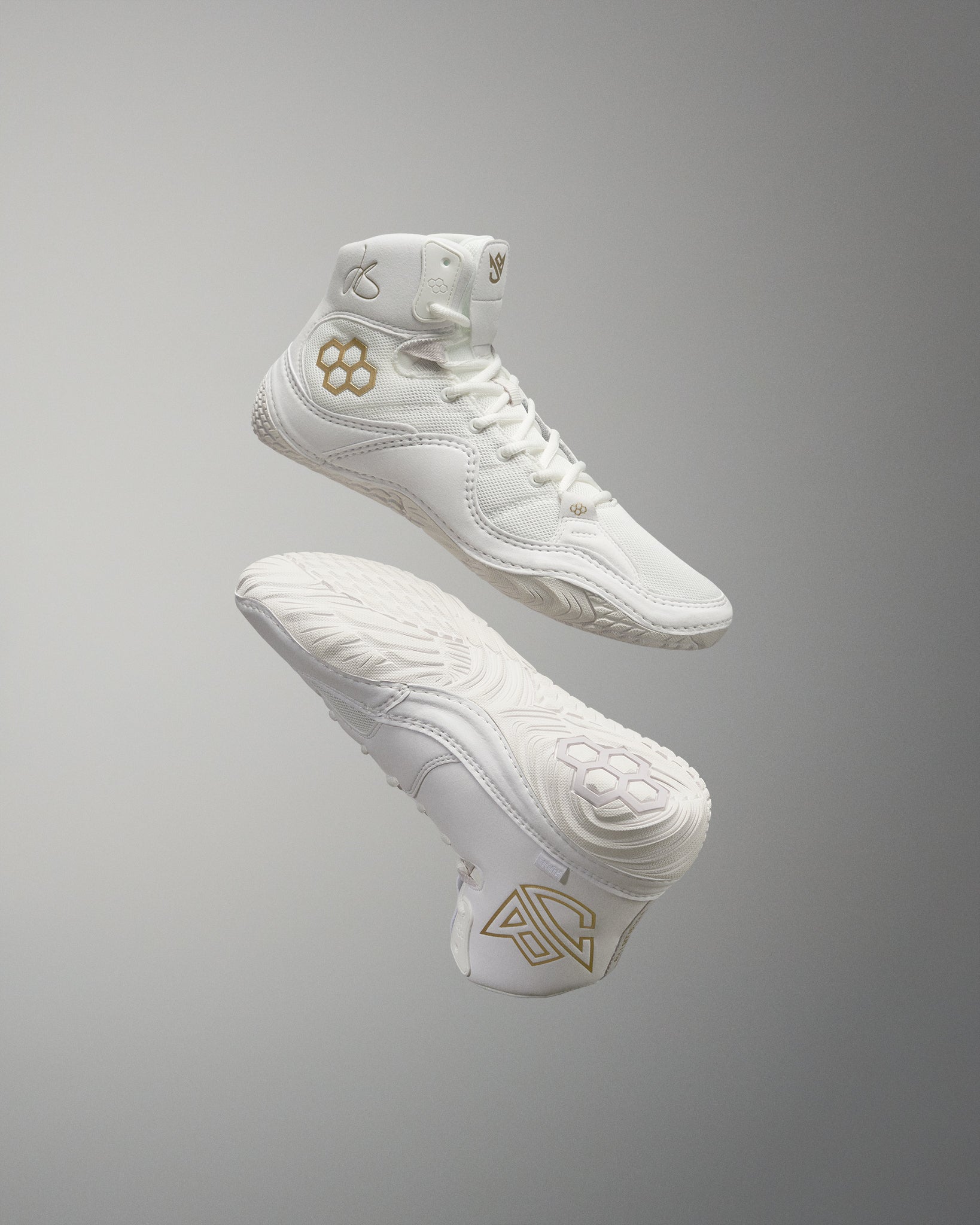 White high-top athletic shoes with modern design elements, gold accents, and textured soles for improved grip, set against a neutral gray background.