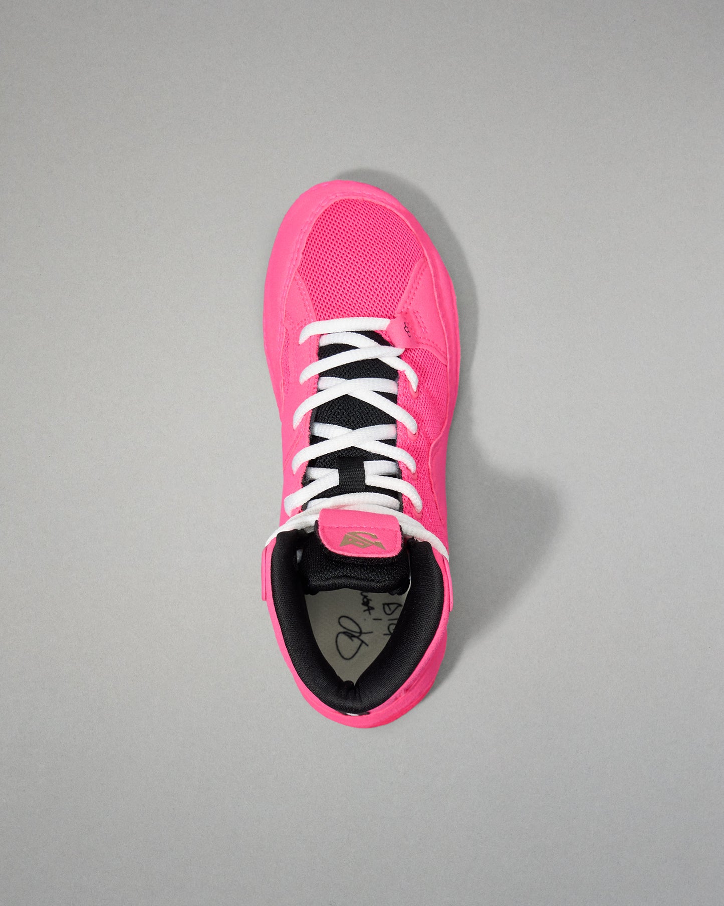 Pink wrestling shoe with black sole on a gray background