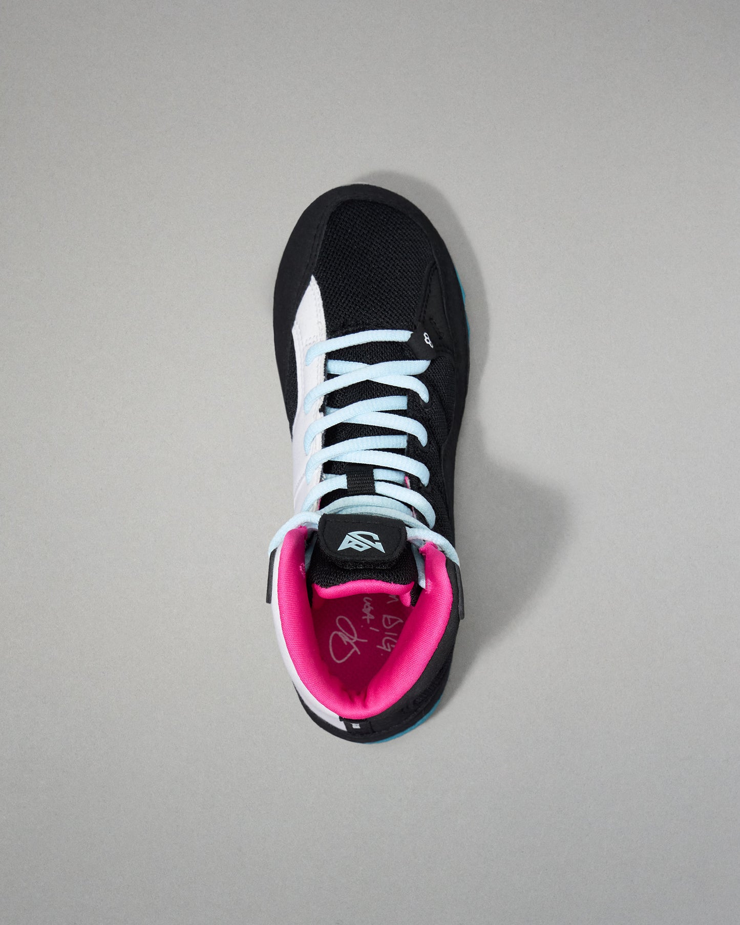 Black wrestling shoe with pink lining on a gray background