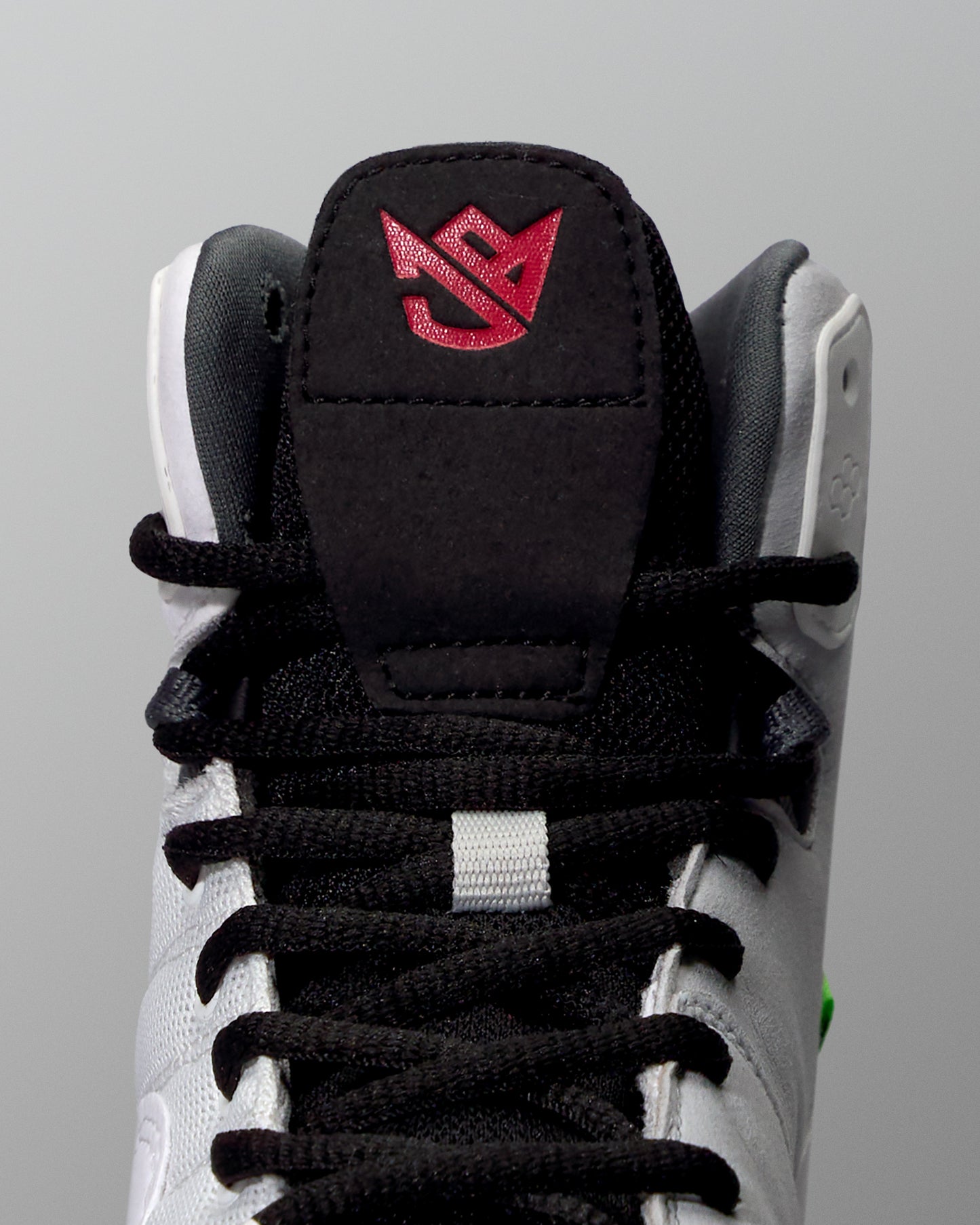 Close-up of a black and white wrestling shoe with a red logo on a gray background