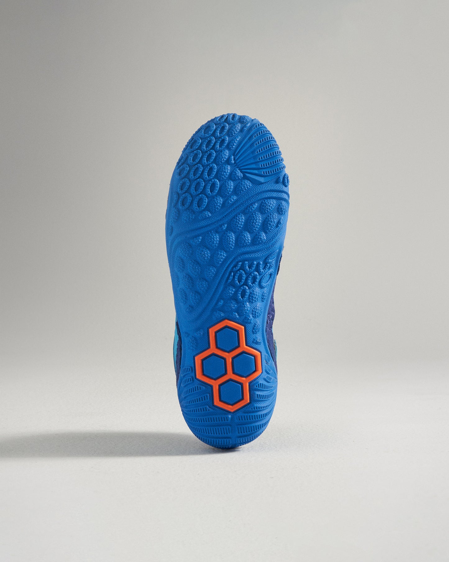 The image showcases the sole of a vibrant blue athletic shoe with an intricate textured pattern and an orange accent design