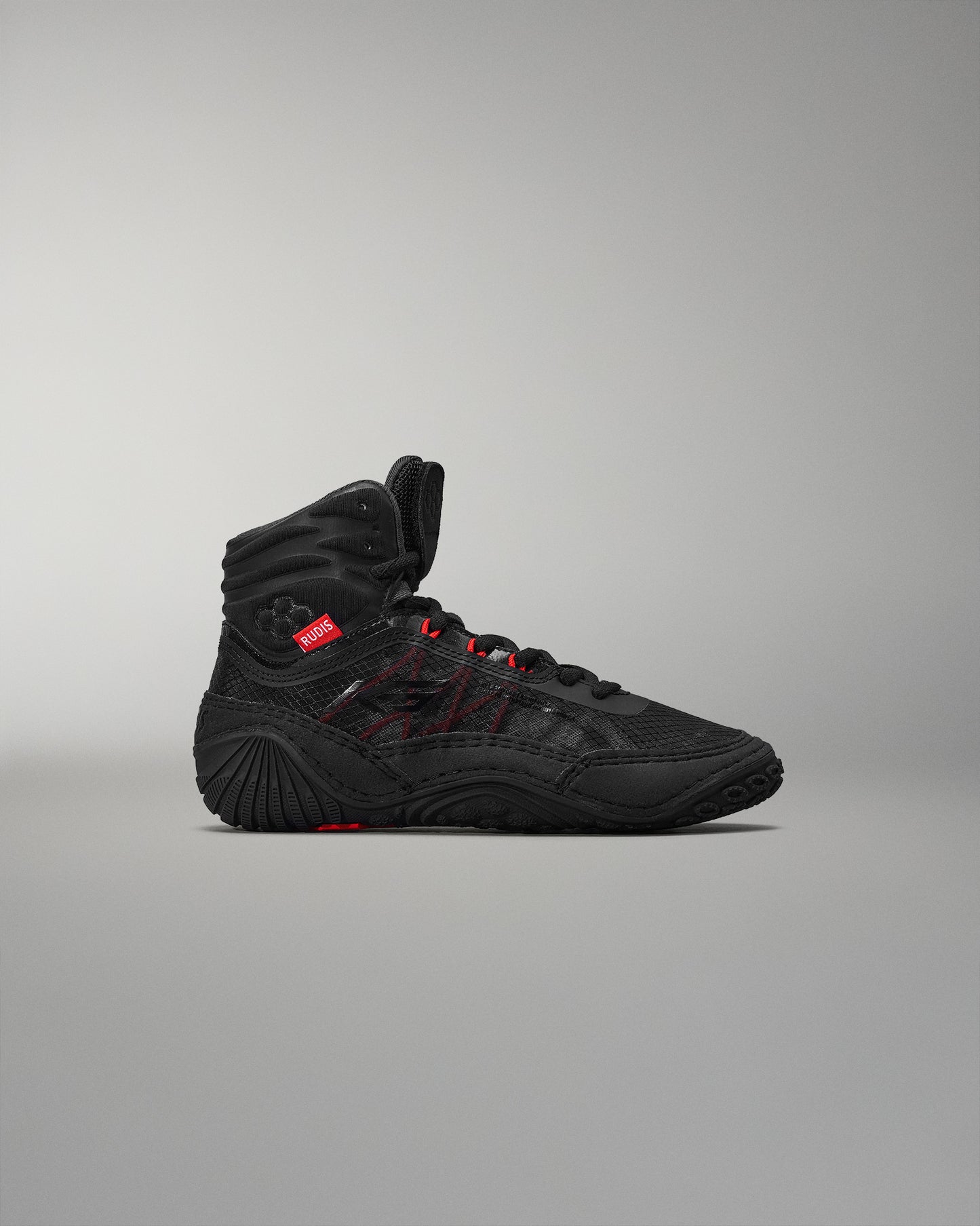 High top black athletic shoe showcasing red accents and textured design, featuring a padded ankle collar for stability against a soft gray background.