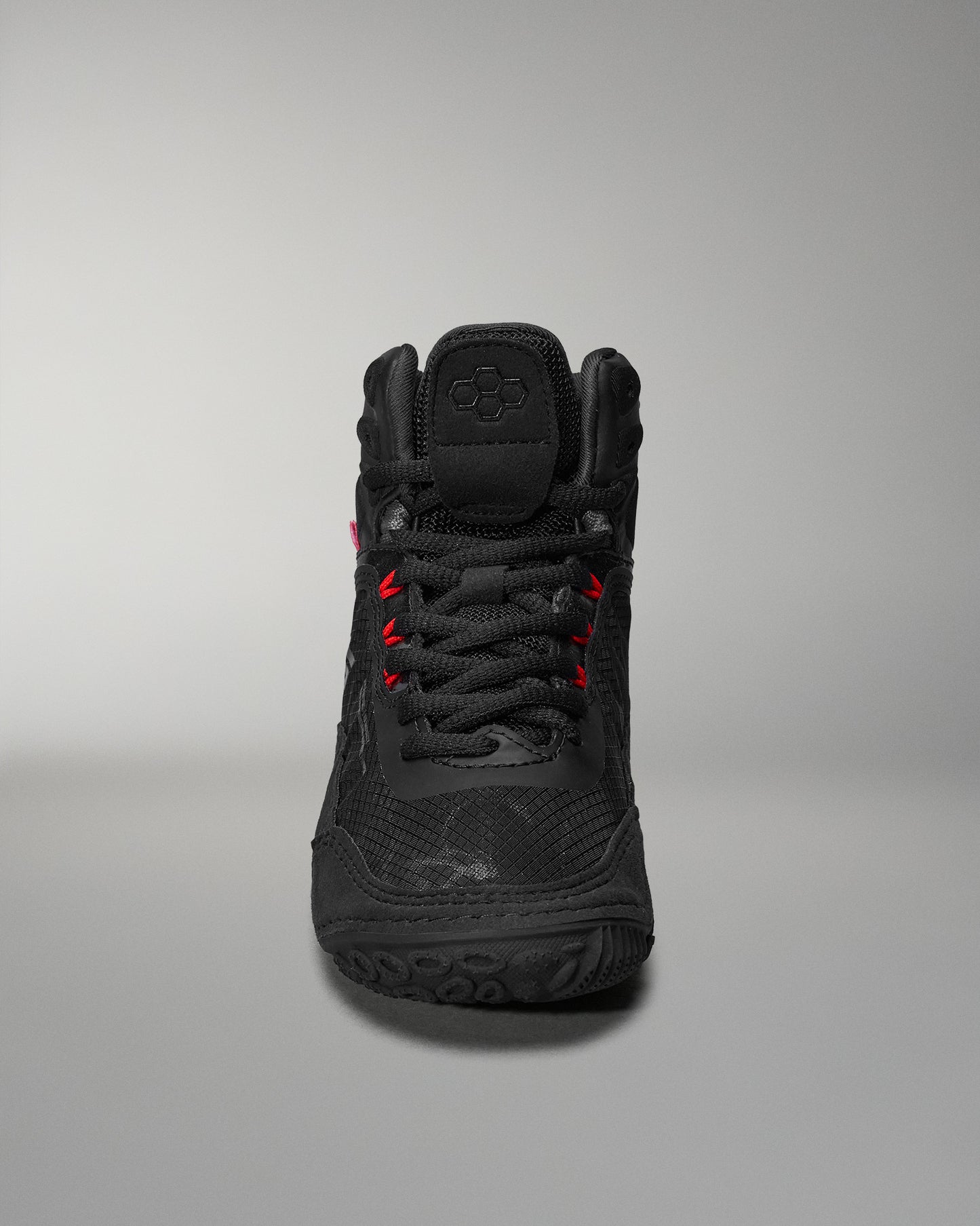 Black high-top athletic shoe features textured detailing and red accents, designed for comfort and performance, presented against a soft gray background.
