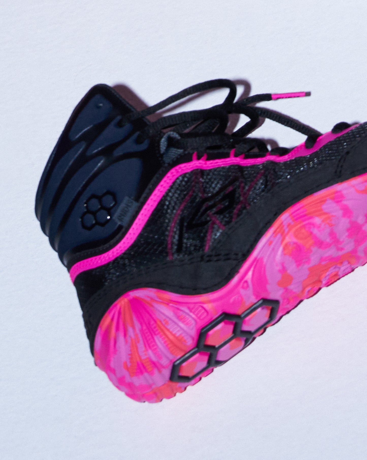 A wrestling shoe in black and vibrant neon pink, featuring a patterned pink and orange midsole, black laces, and a black protective ankle collar.