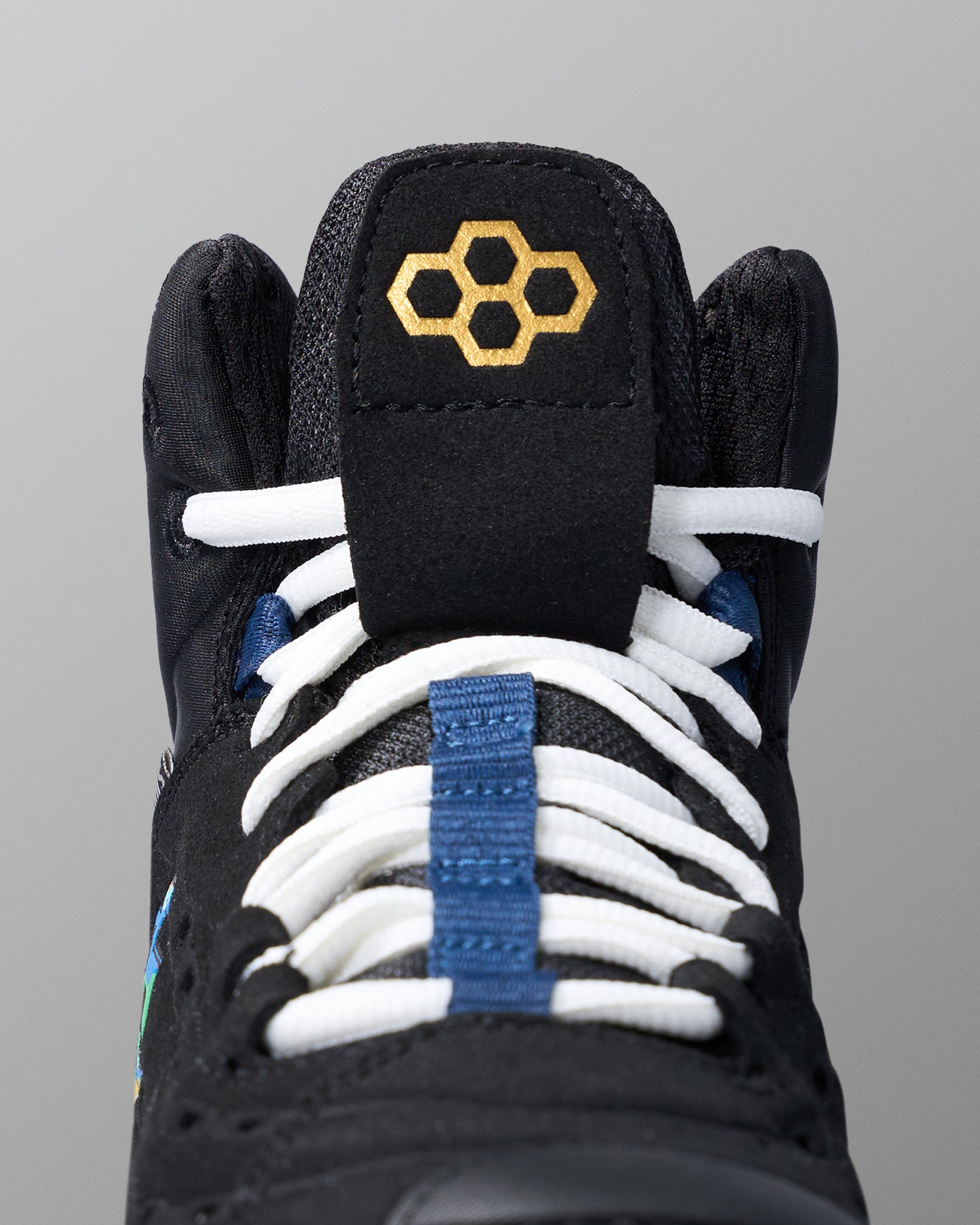 Black wrestling shoe with white laces and blue accents on a gray background