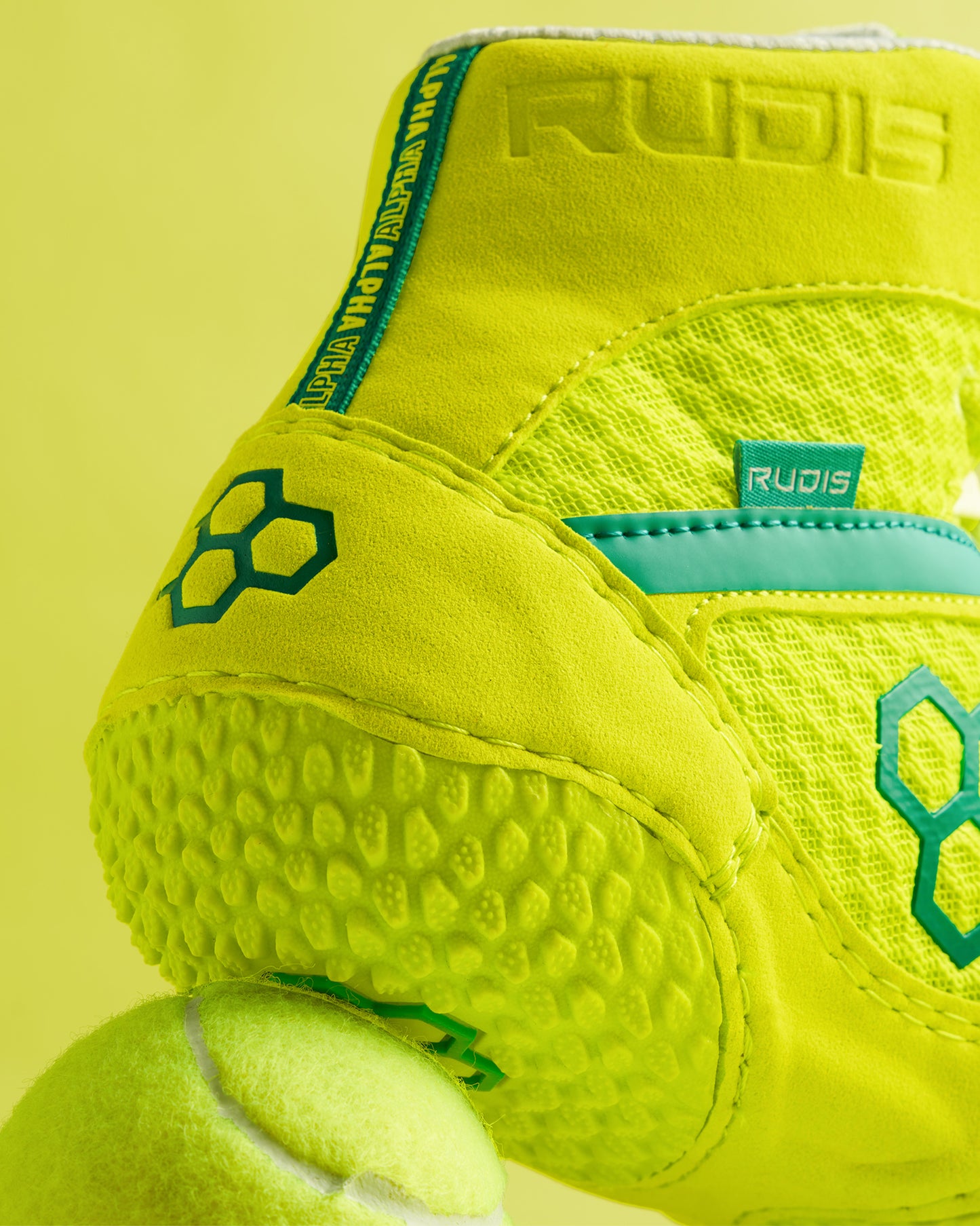 A close-up view of a vibrant neon yellow athletic shoe paired with a tennis ball showcasing details of the shoes textured design and branding