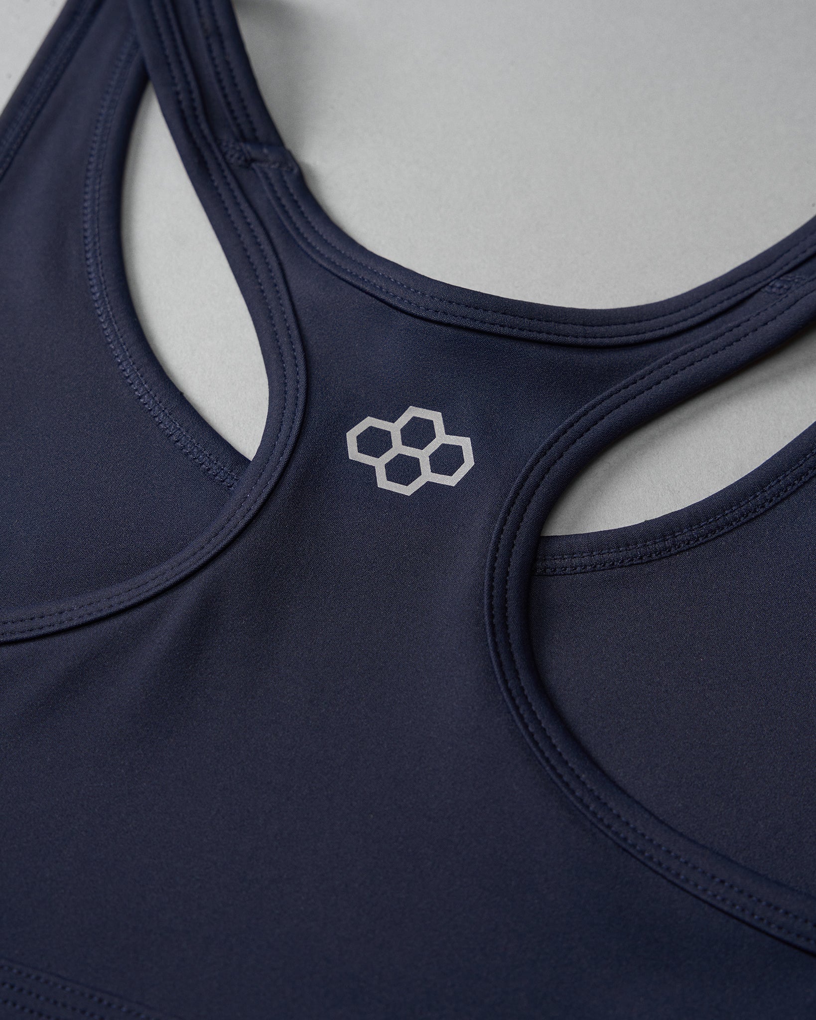 Navy blue sports bra with a hexagonal logo on a light gray background