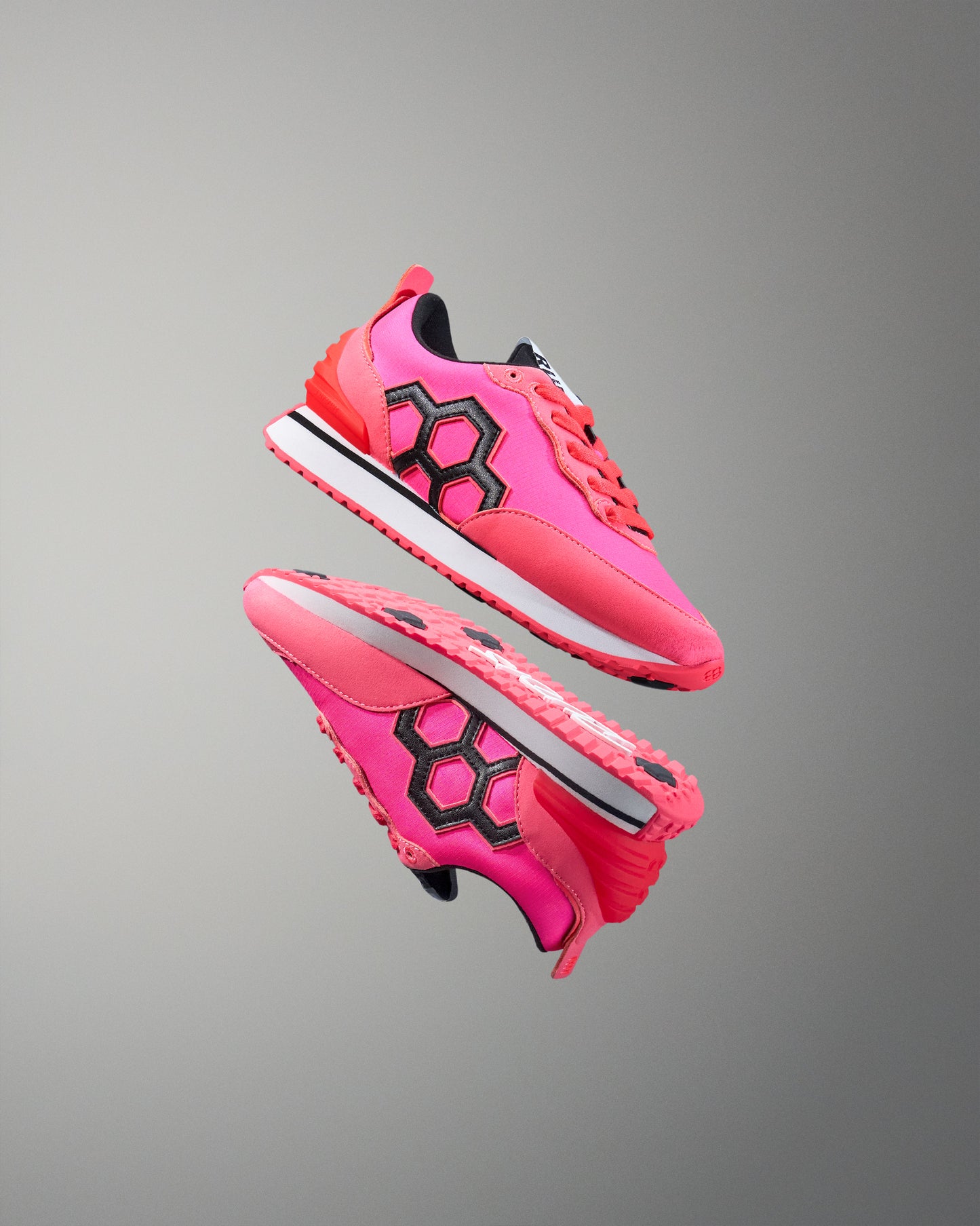 Pink street shoes with black hexagonal pattern on a gray background