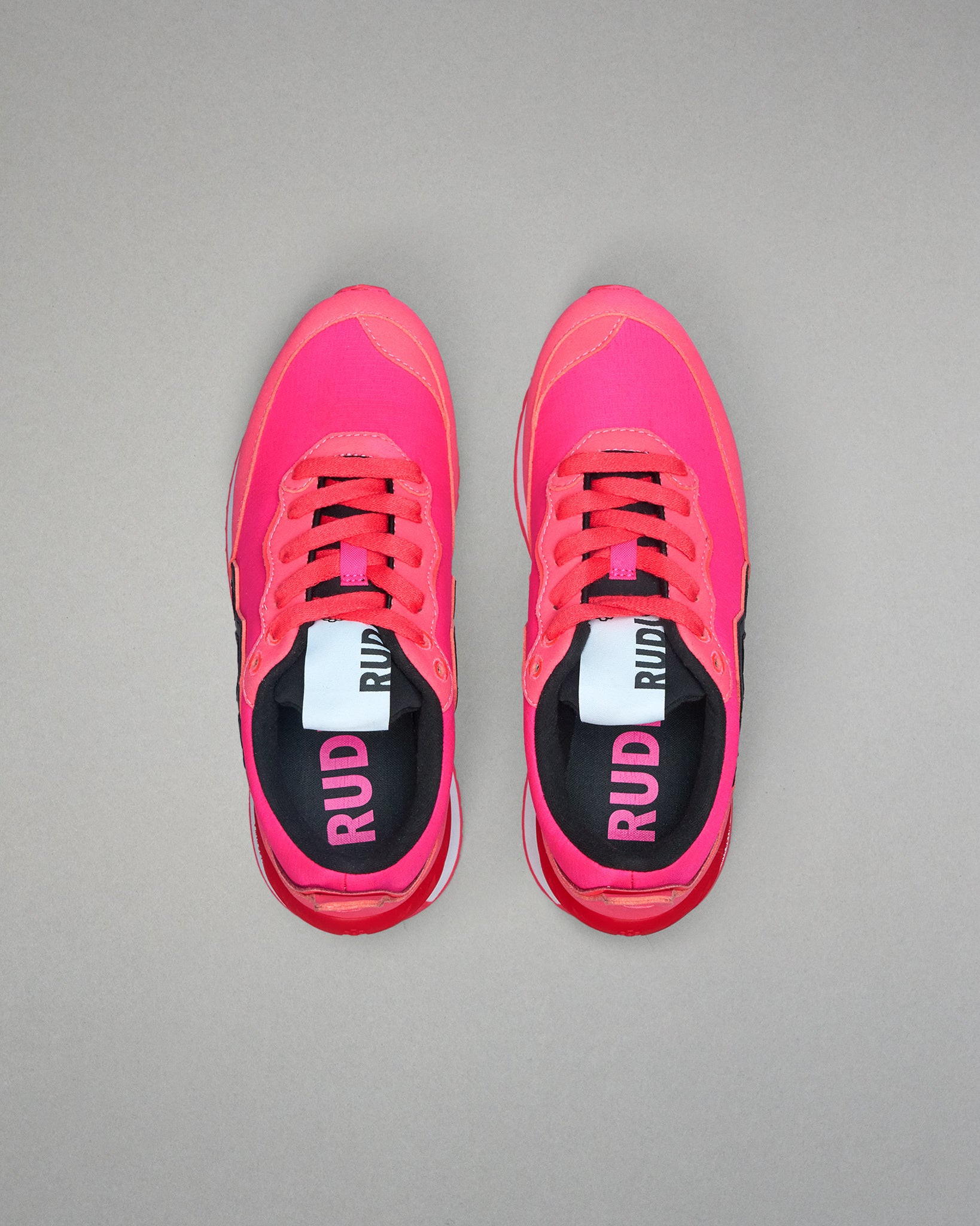 Pair of pink running shoes with 'RUD' branding on a gray background