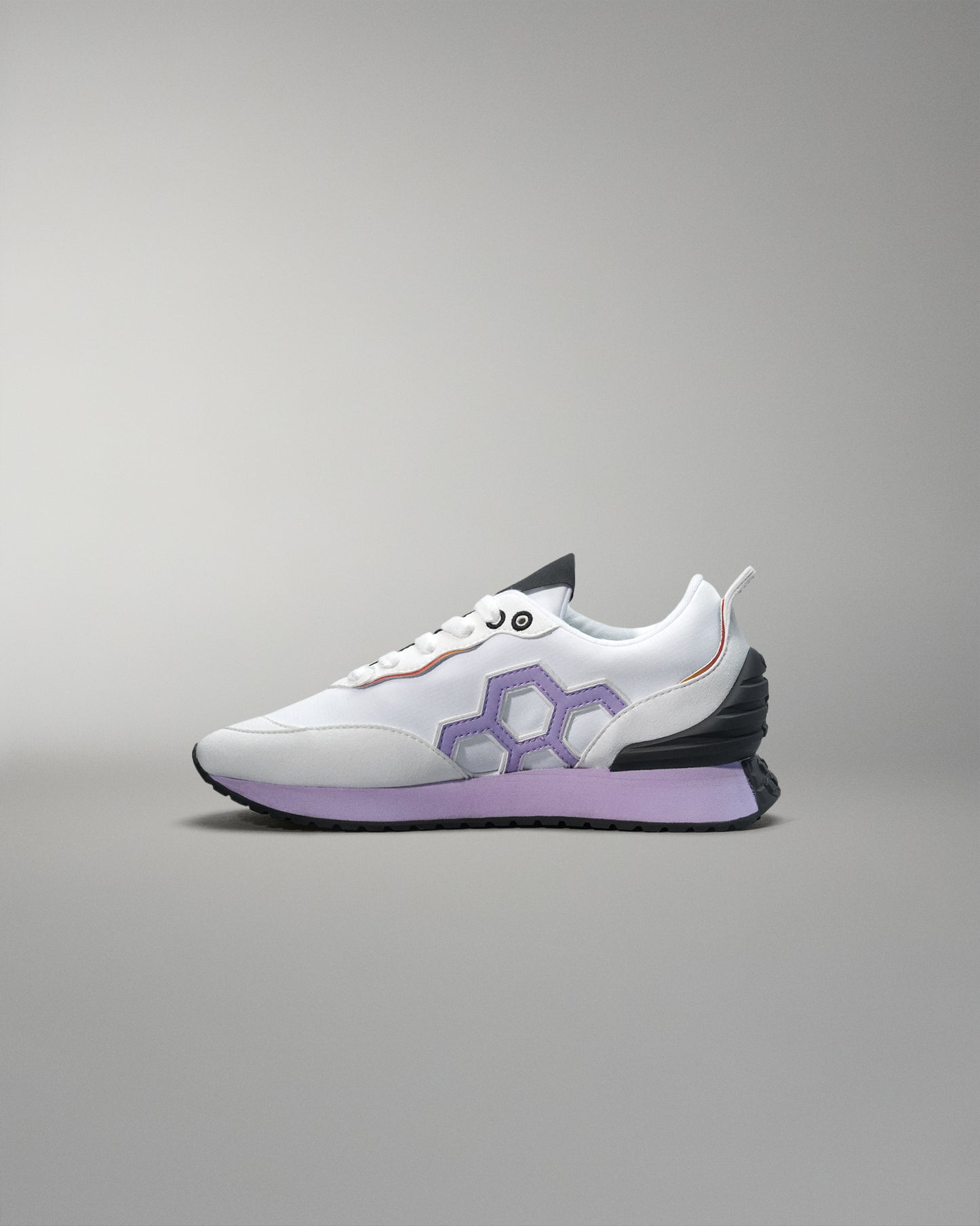 White sneaker with a purple logo on a gray background