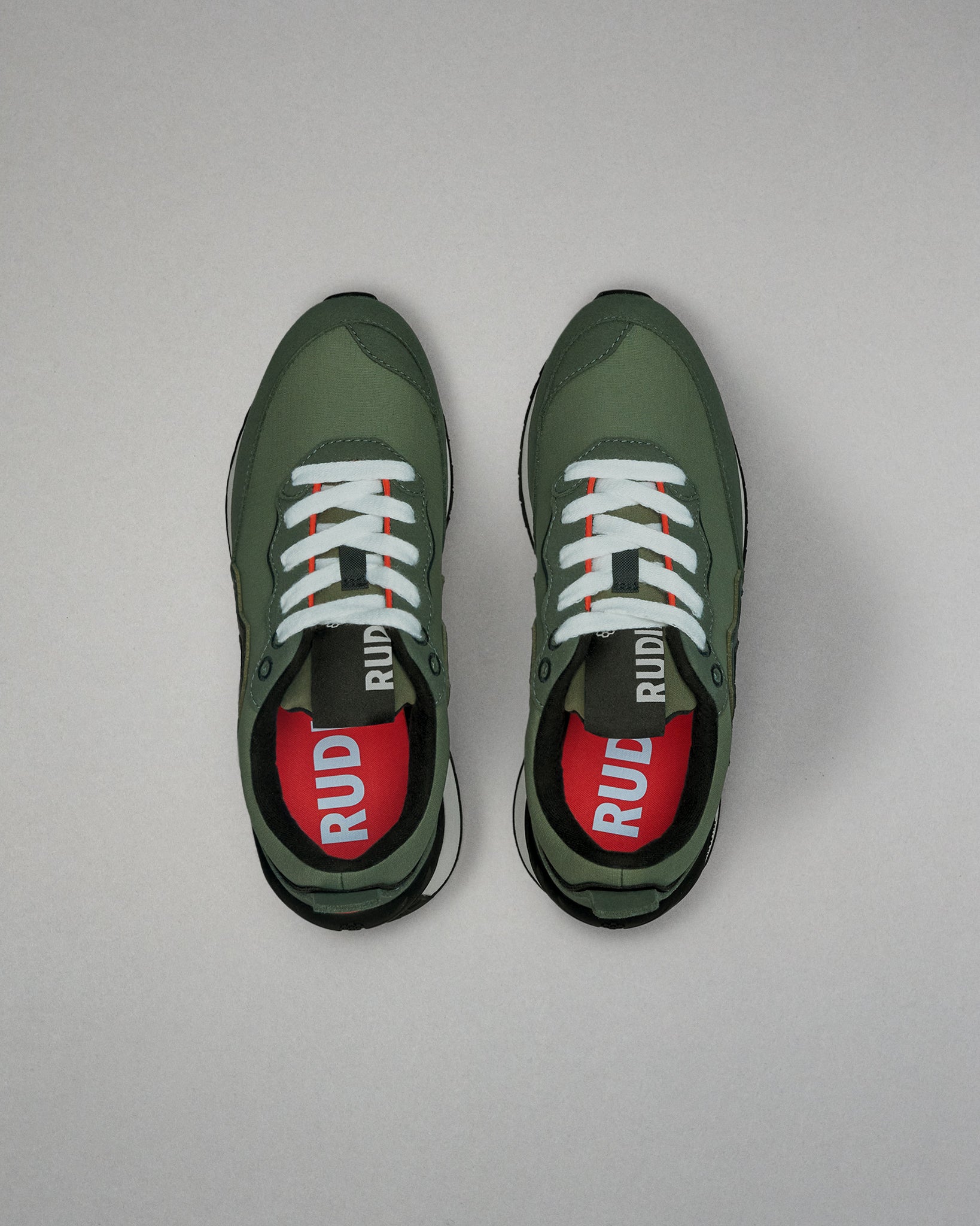 Green running shoes with white laces on a gray background