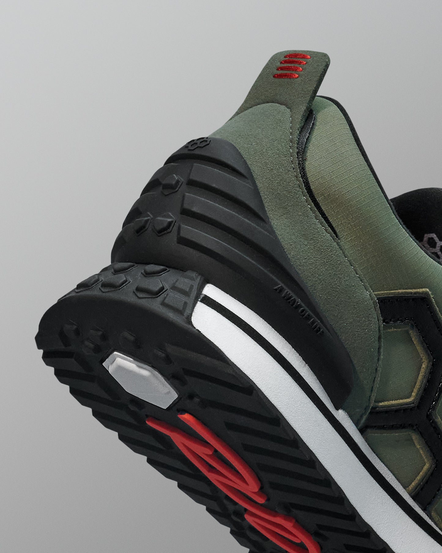 Close-up of a green and black sneaker with red accents on a gray background