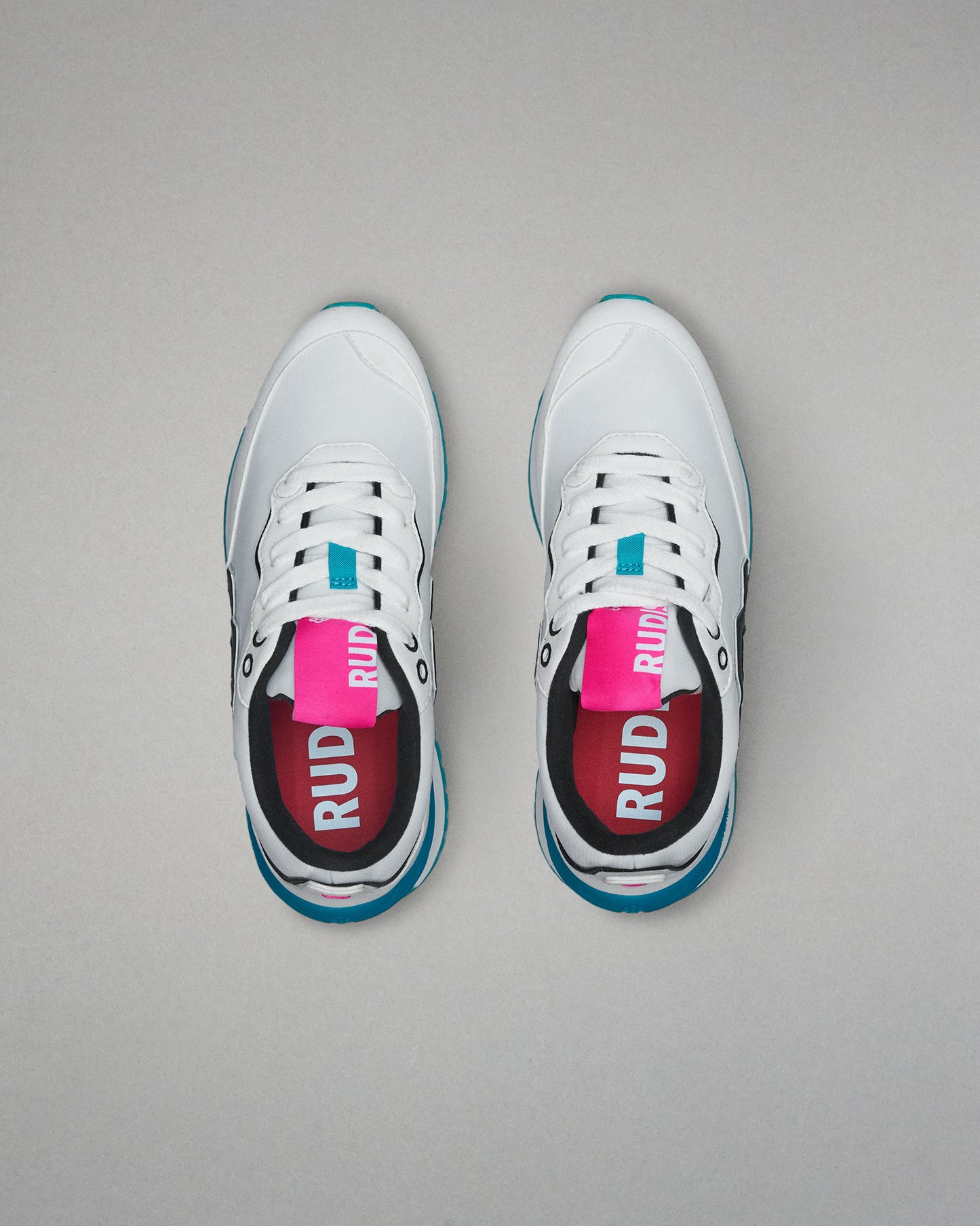 White sneakers with blue soles and pink labels on a gray background
