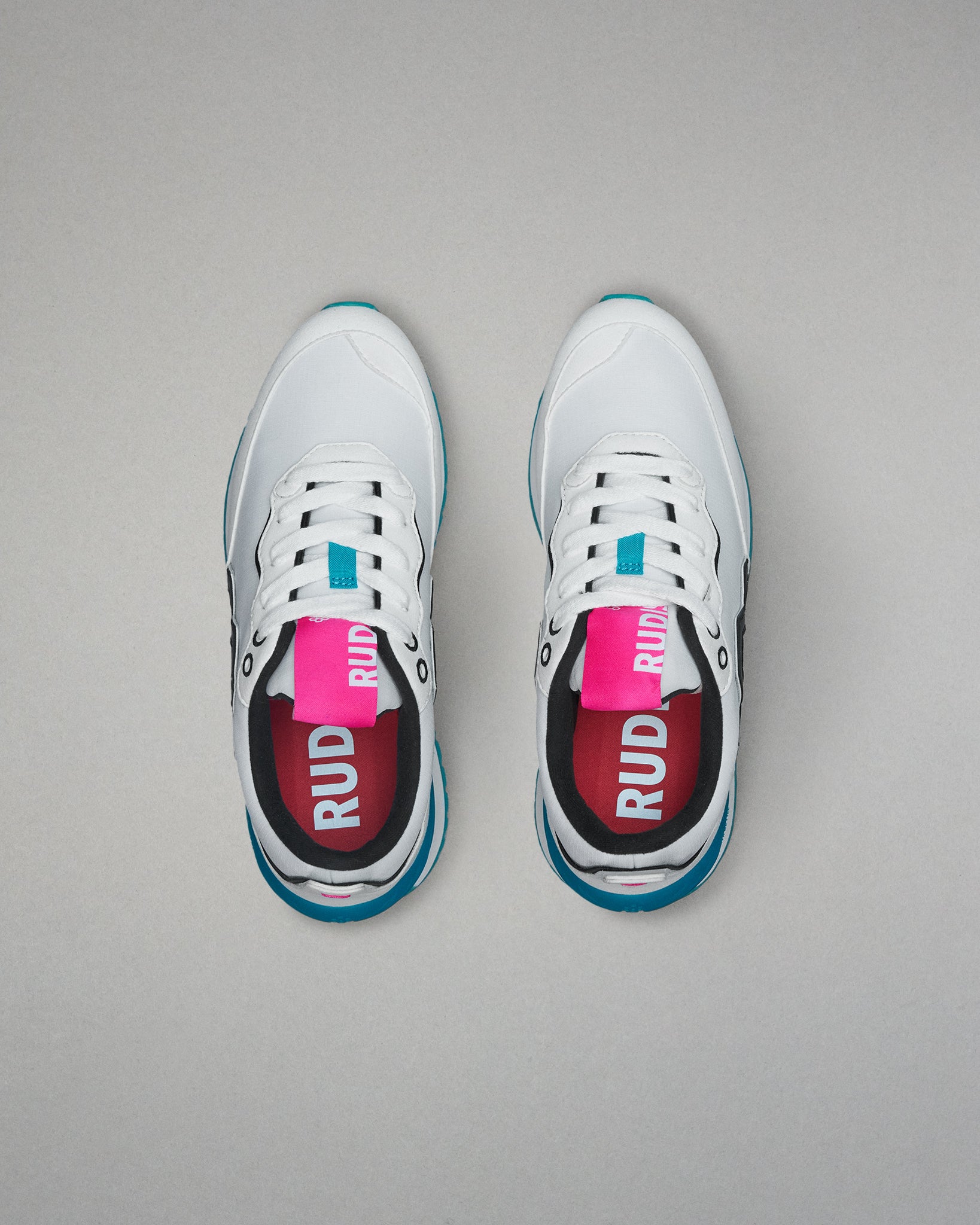 White sneakers with blue soles and pink labels on a gray background