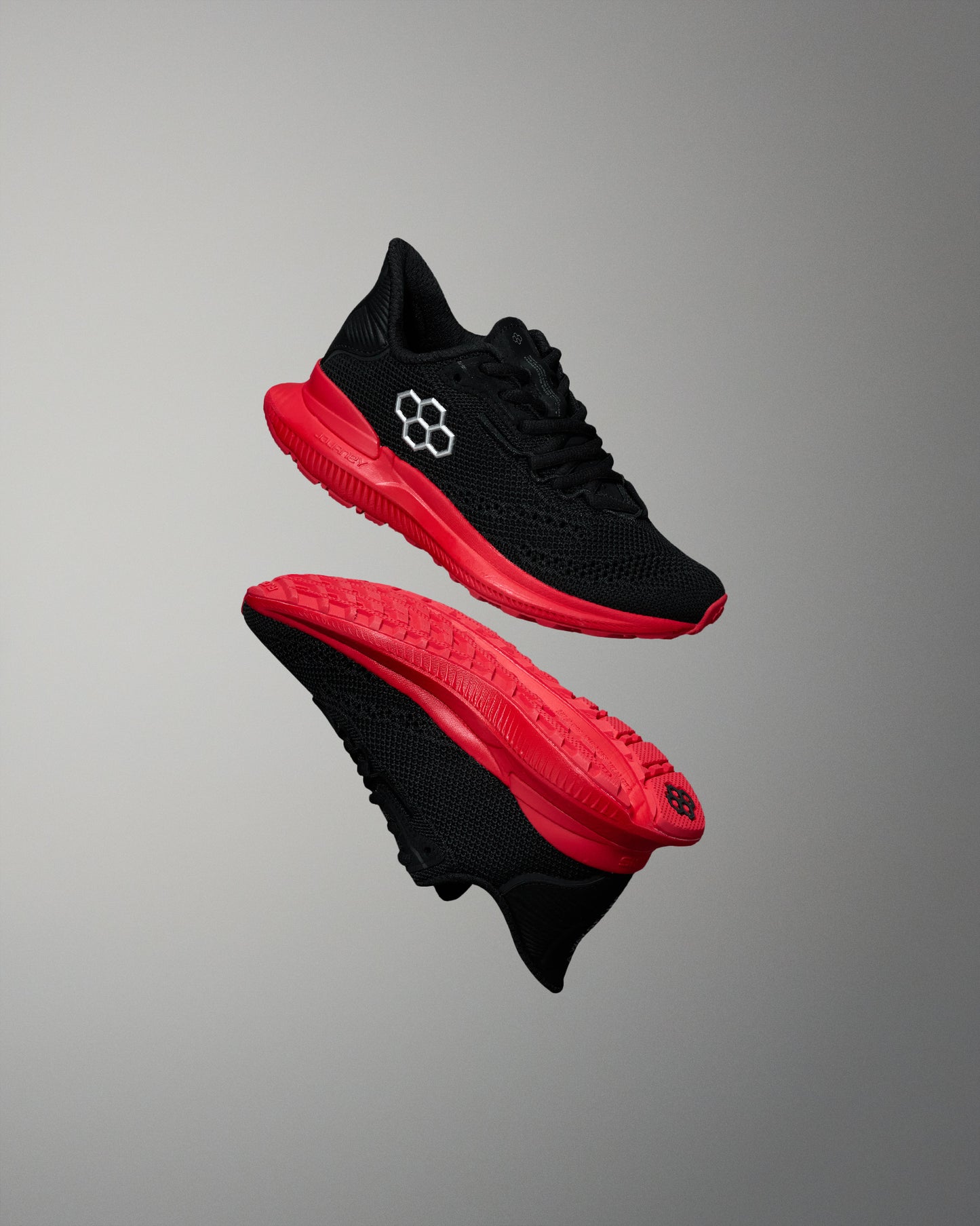 Side and bottom view of black RUDIS training shoes with bright red midsoles and outsoles. Features a white hexagon logo on the upper and red tread detail. Displayed against a neutral gray background.
