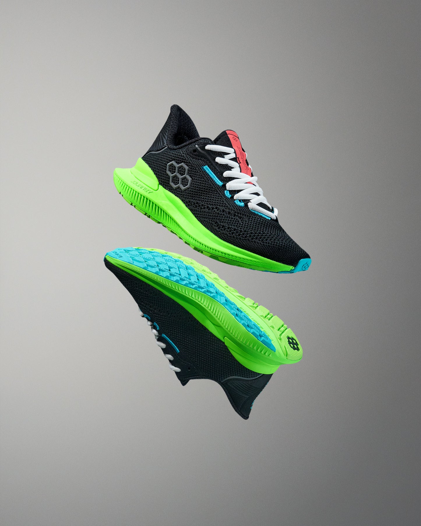 Black running shoes with green sole on a gray background