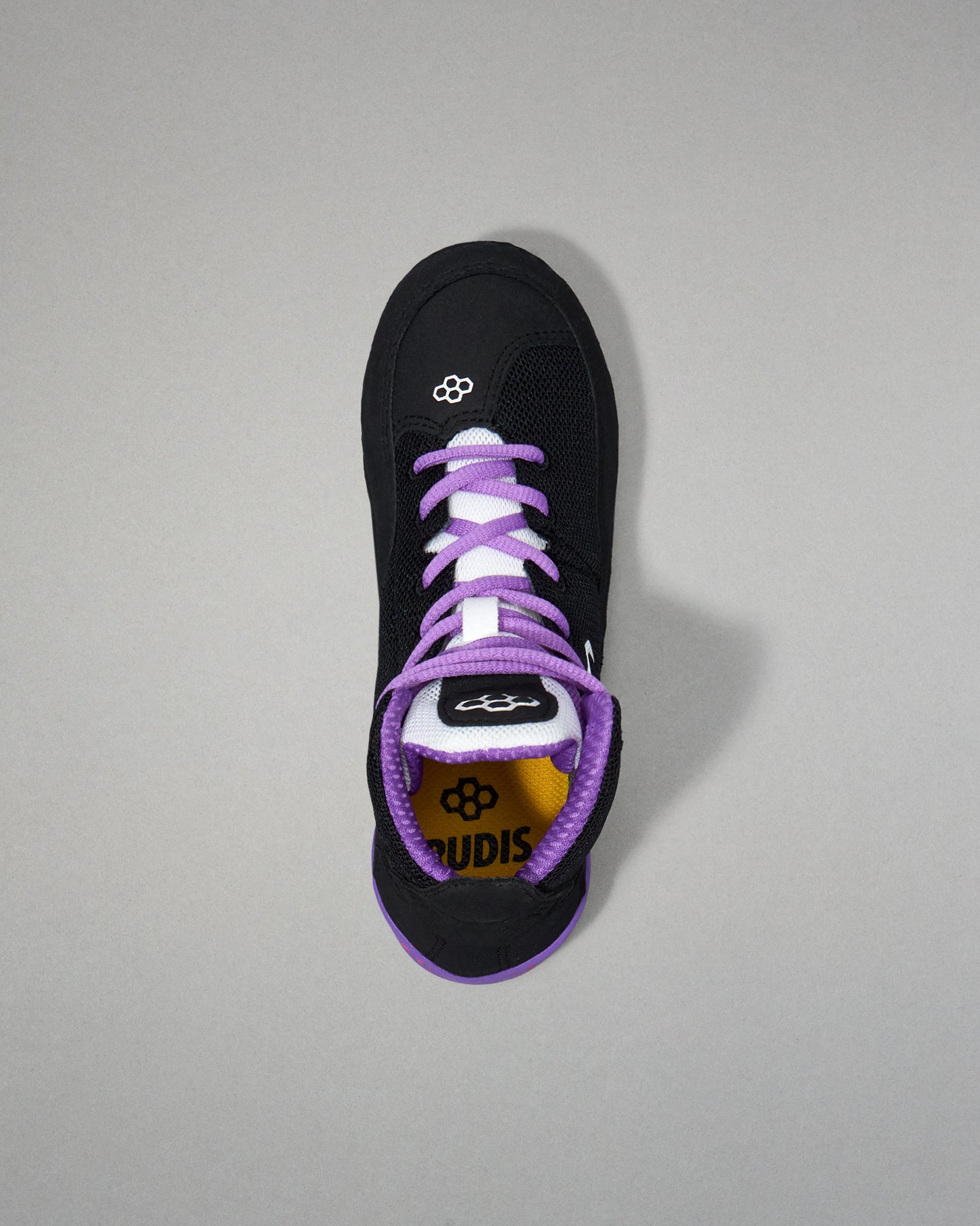 Black sneaker with purple laces on a gray background