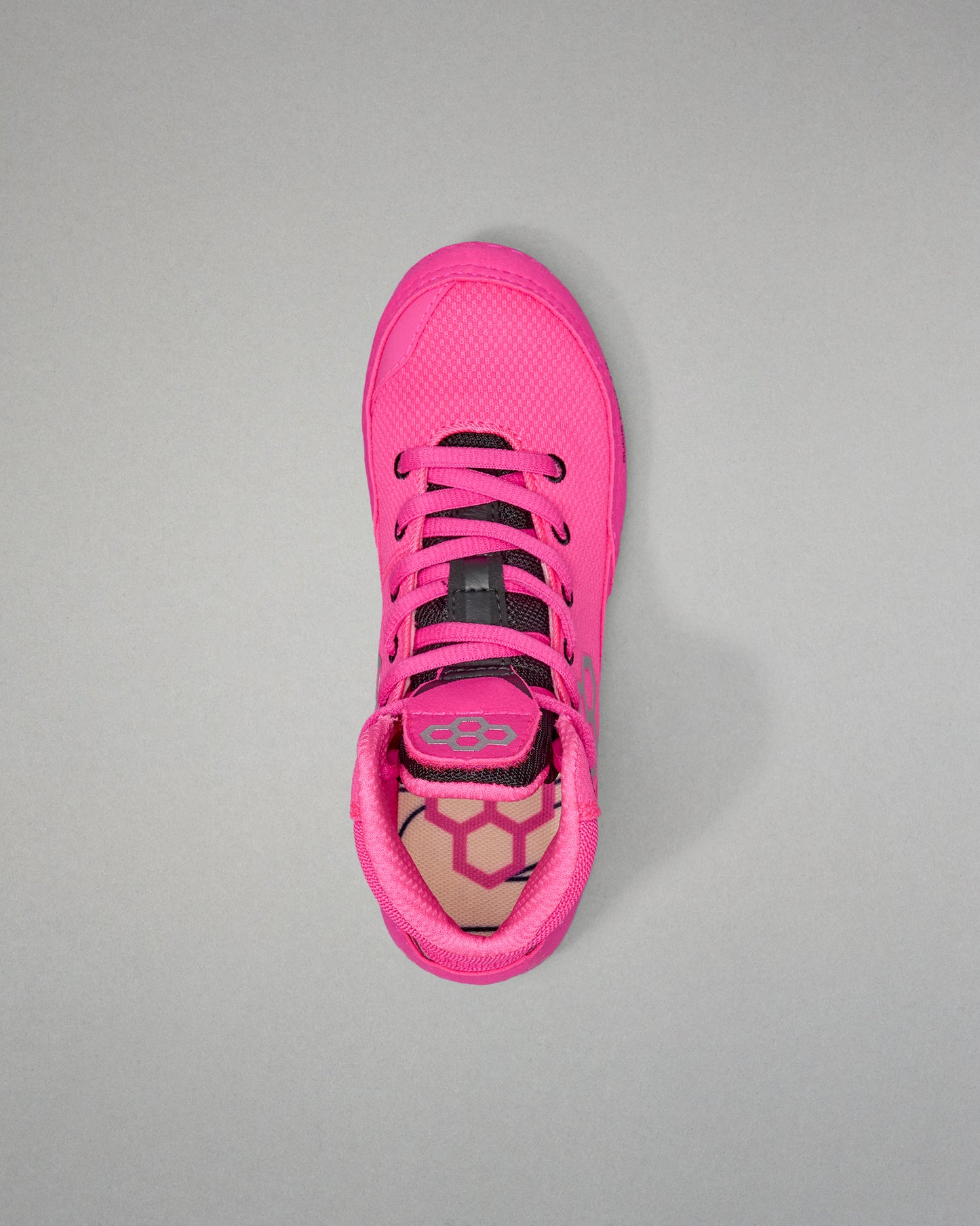 Pink athletic shoe with black laces on a gray background